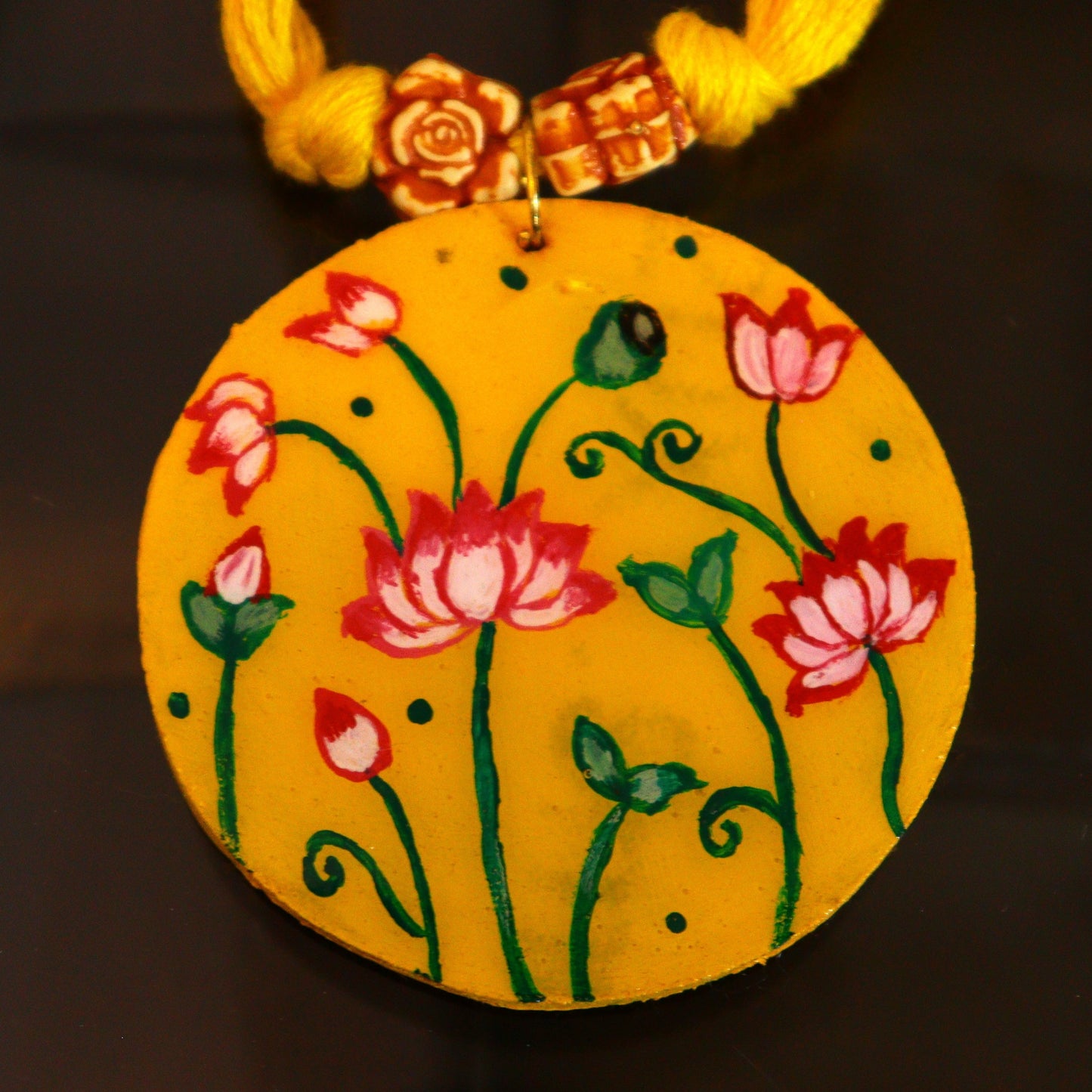 Decorative yellow pendant with floral design on a dark background