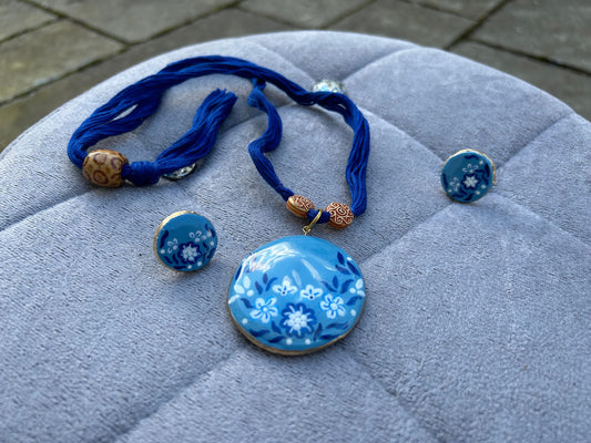 Blue floral jewelry set on a textured surface