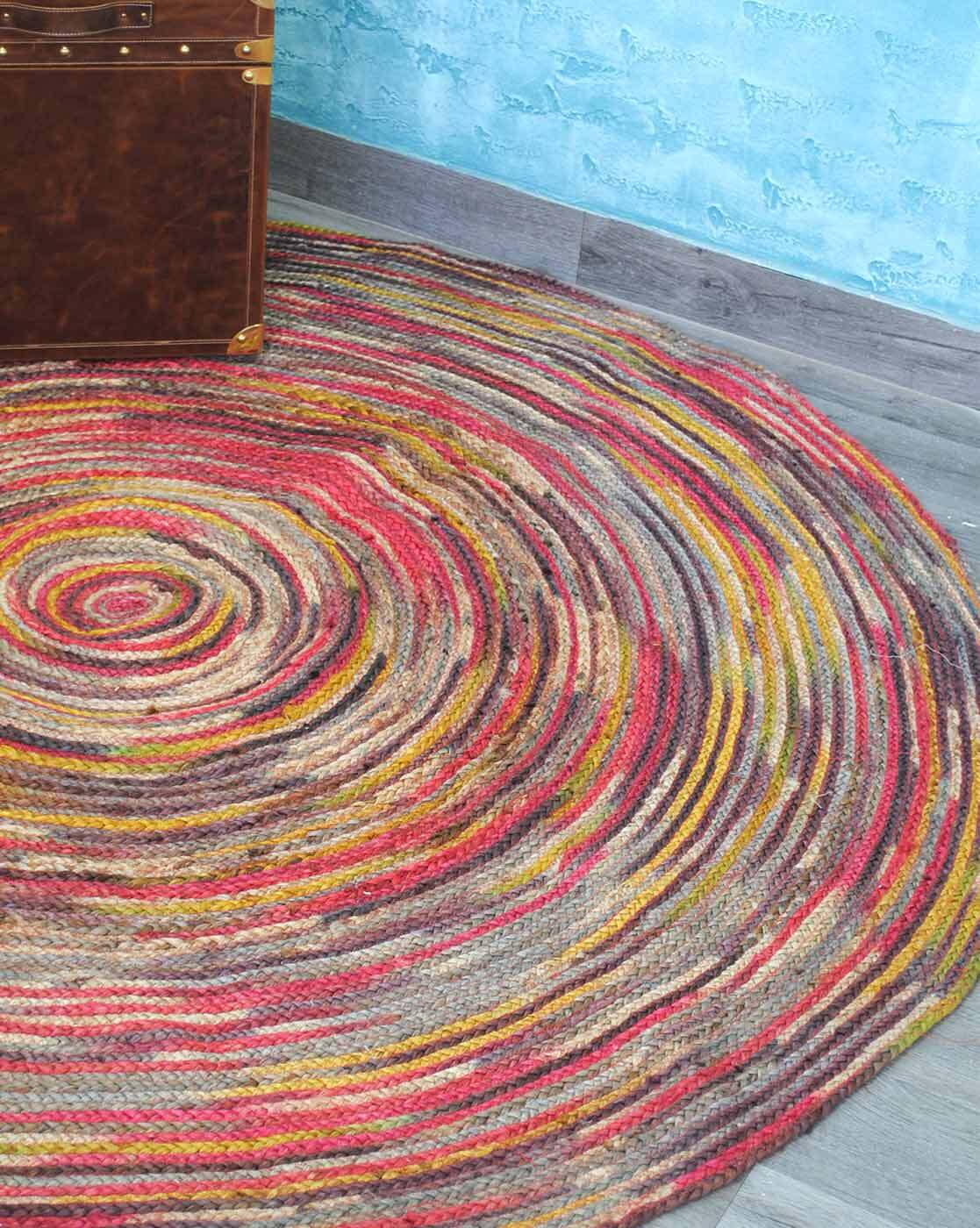 Multicolored circular rug on a wooden floor with a blue wall in the background