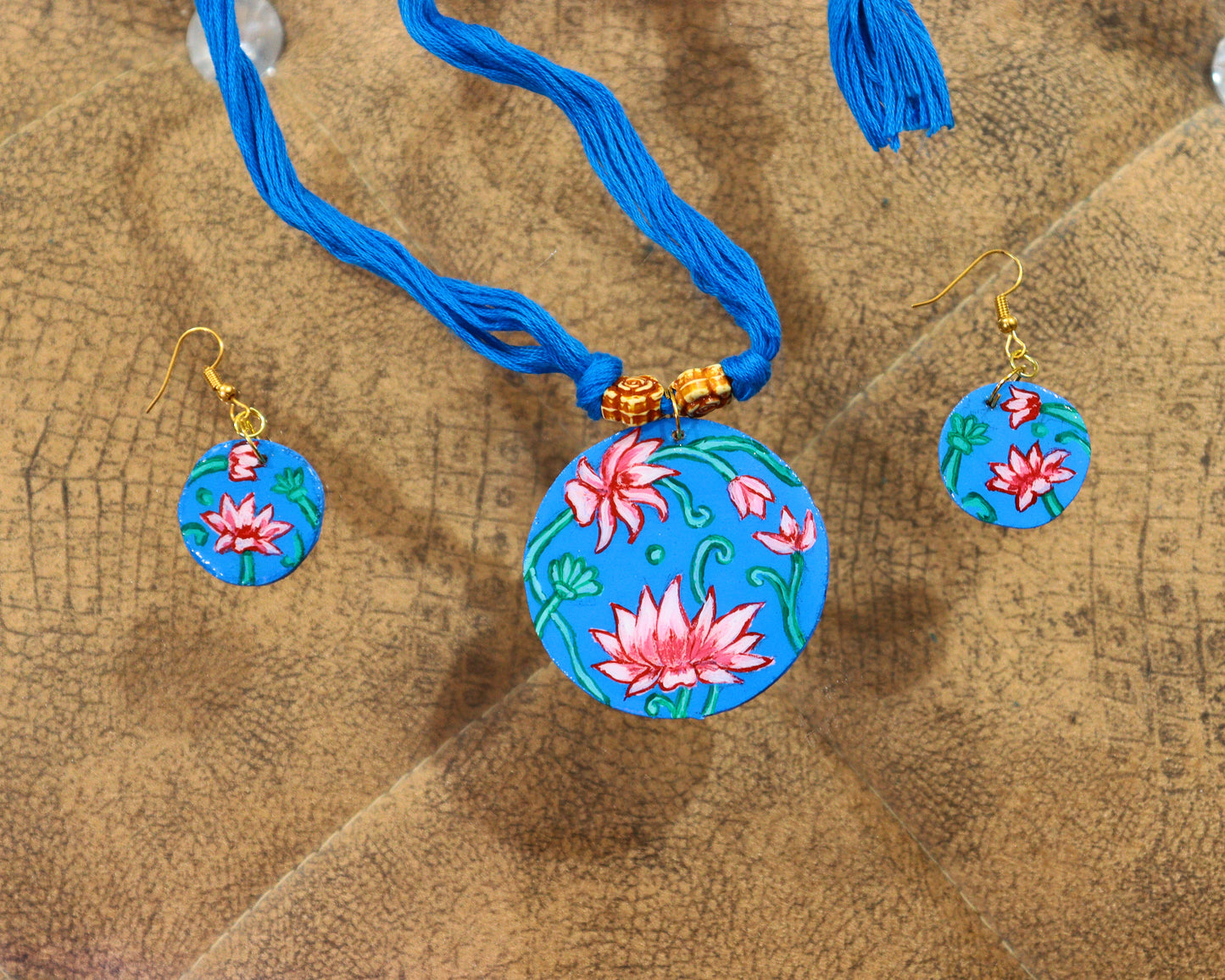 Necklace and earrings with floral designs on a wooden surface