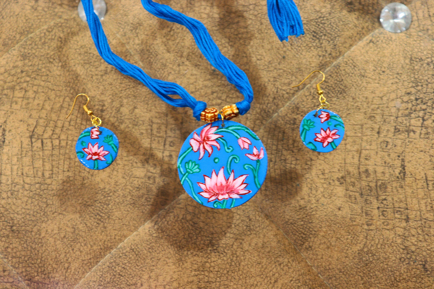 Colorful floral pendant necklace with matching earrings on a wooden surface
