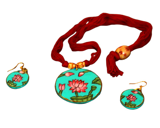 Turquoise floral pendant with matching earrings on a dark surface