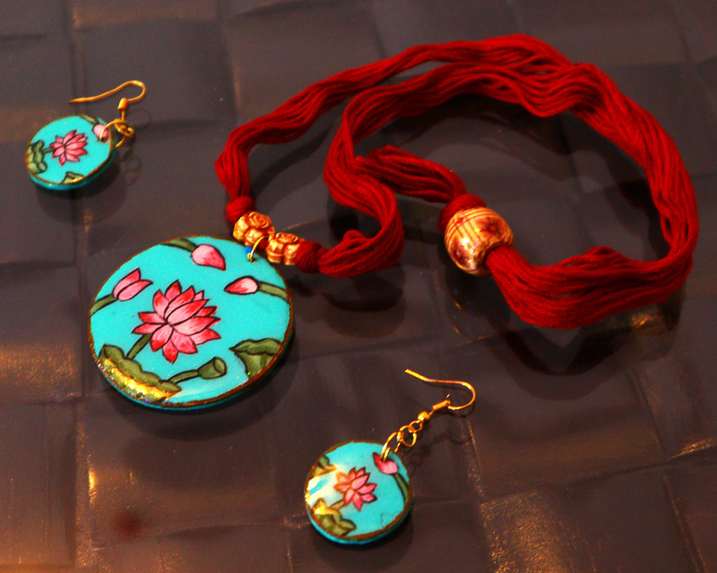 Jewelry set with turquoise earrings and pendant on a reflective surface
