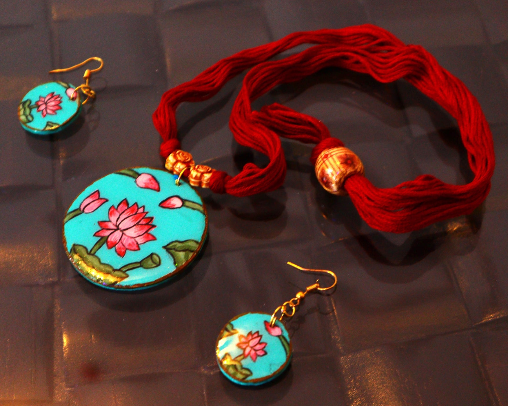 Jewelry set with turquoise earrings and pendant on a reflective surface