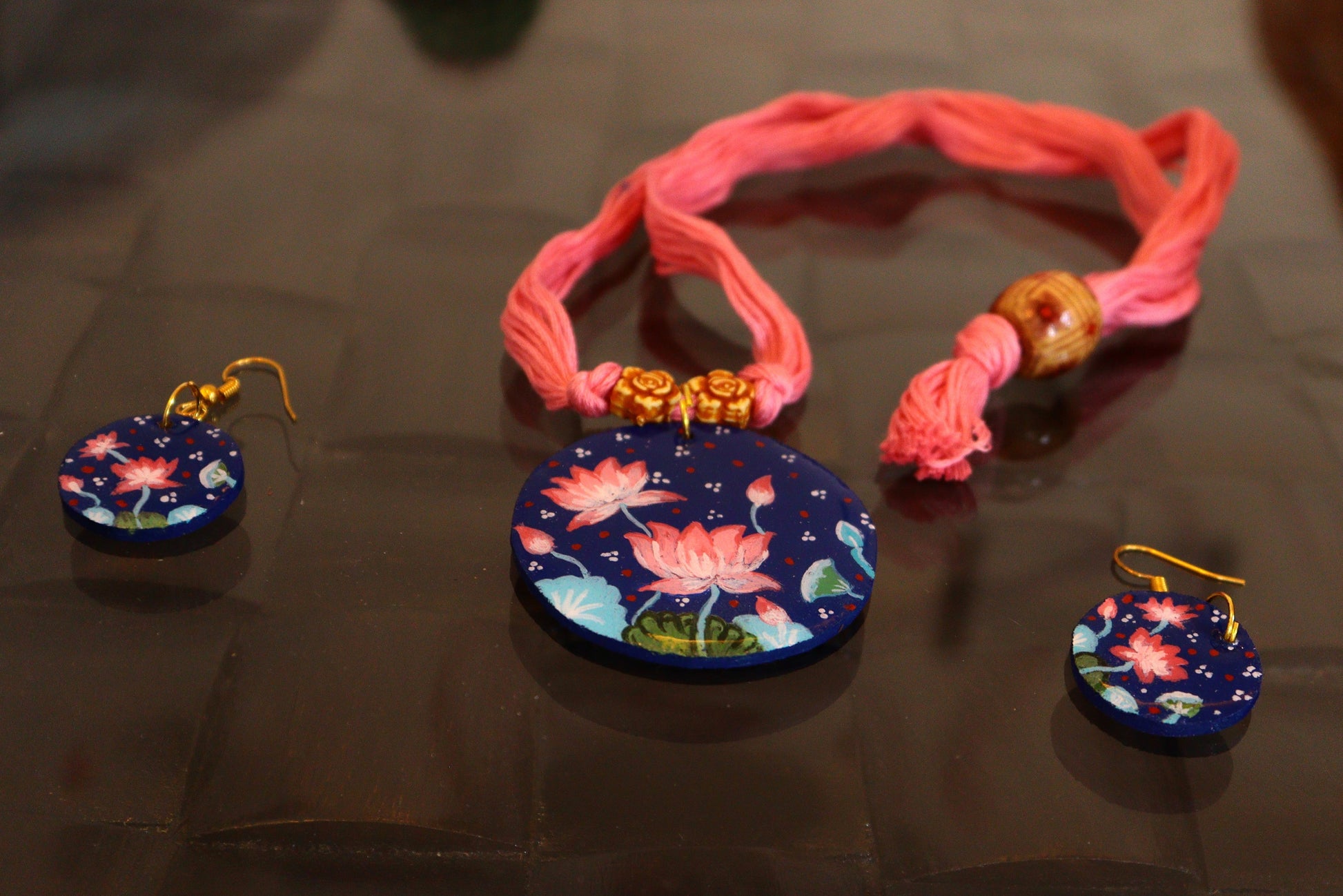 Pink bracelet with floral charms on a reflective surface