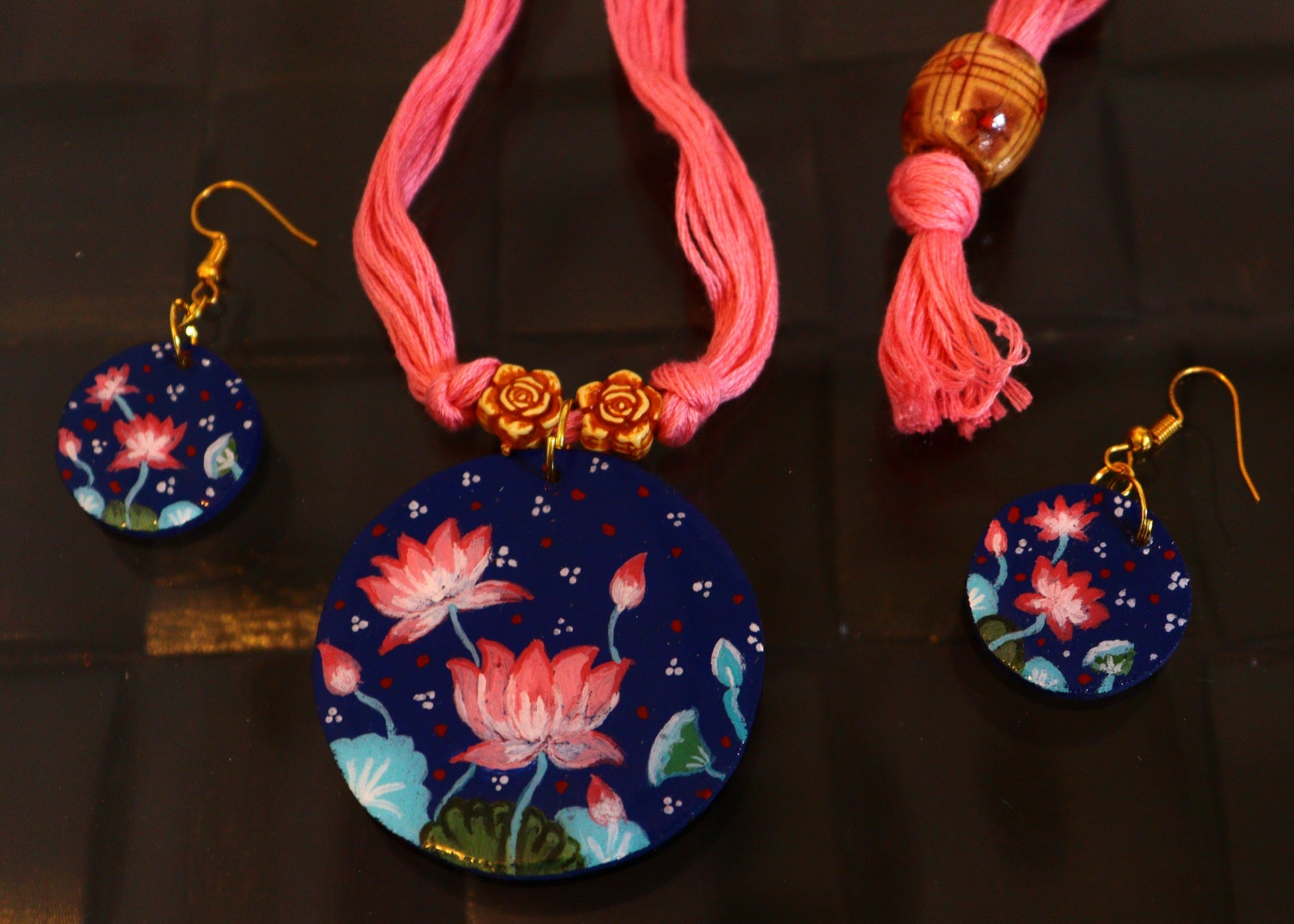Necklace with floral pendant and matching earrings on a dark background