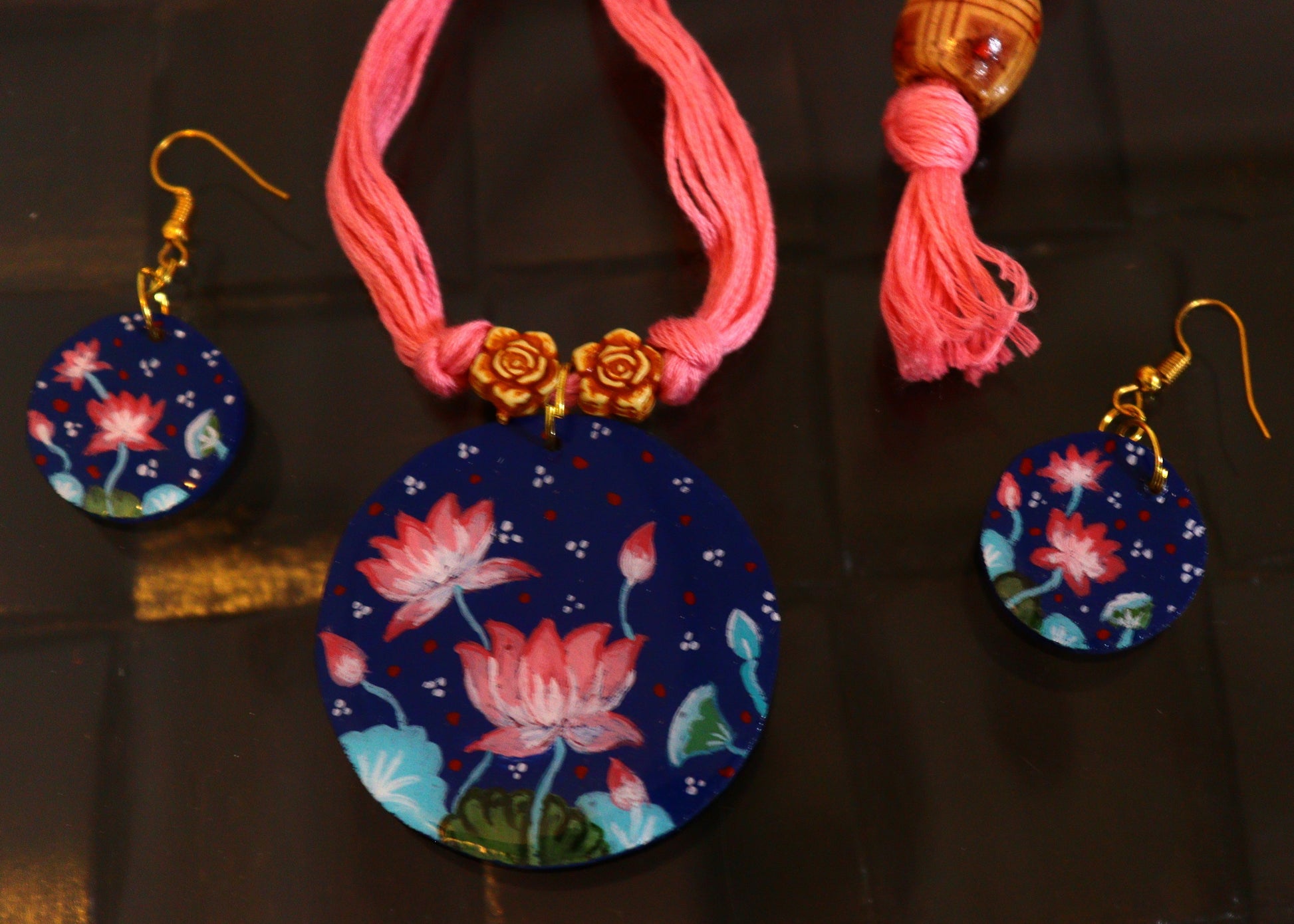 Necklace with floral pendant and matching earrings on a dark background
