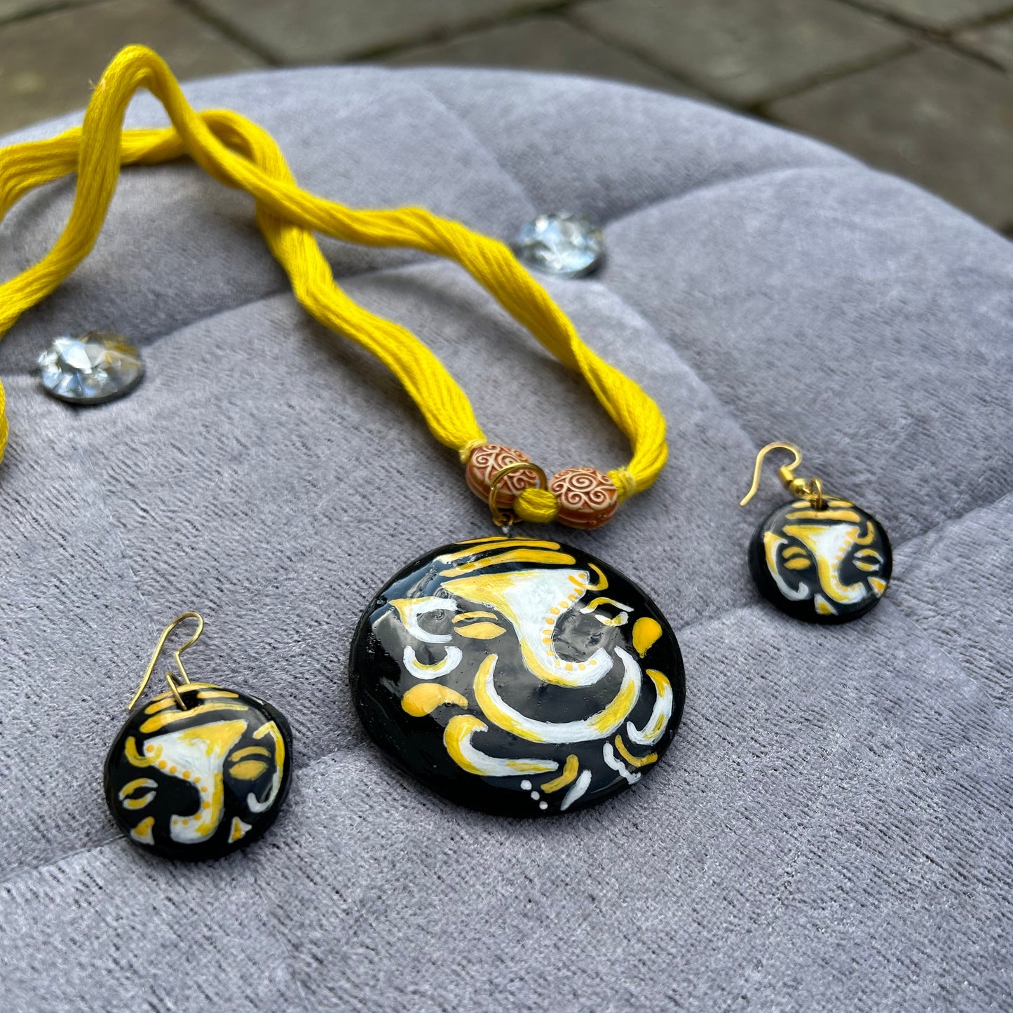 Black and gold earrings with a yellow cord on a gray fabric background