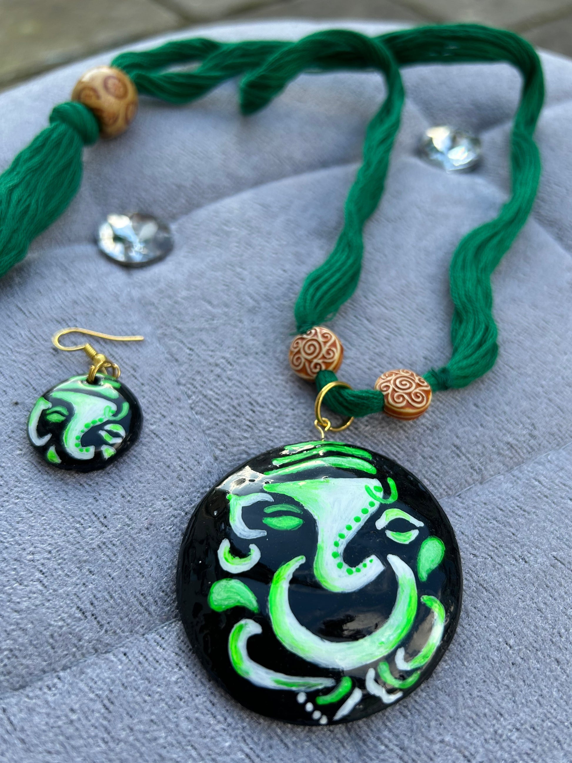 Green and black jewelry set with tassels on a gray surface