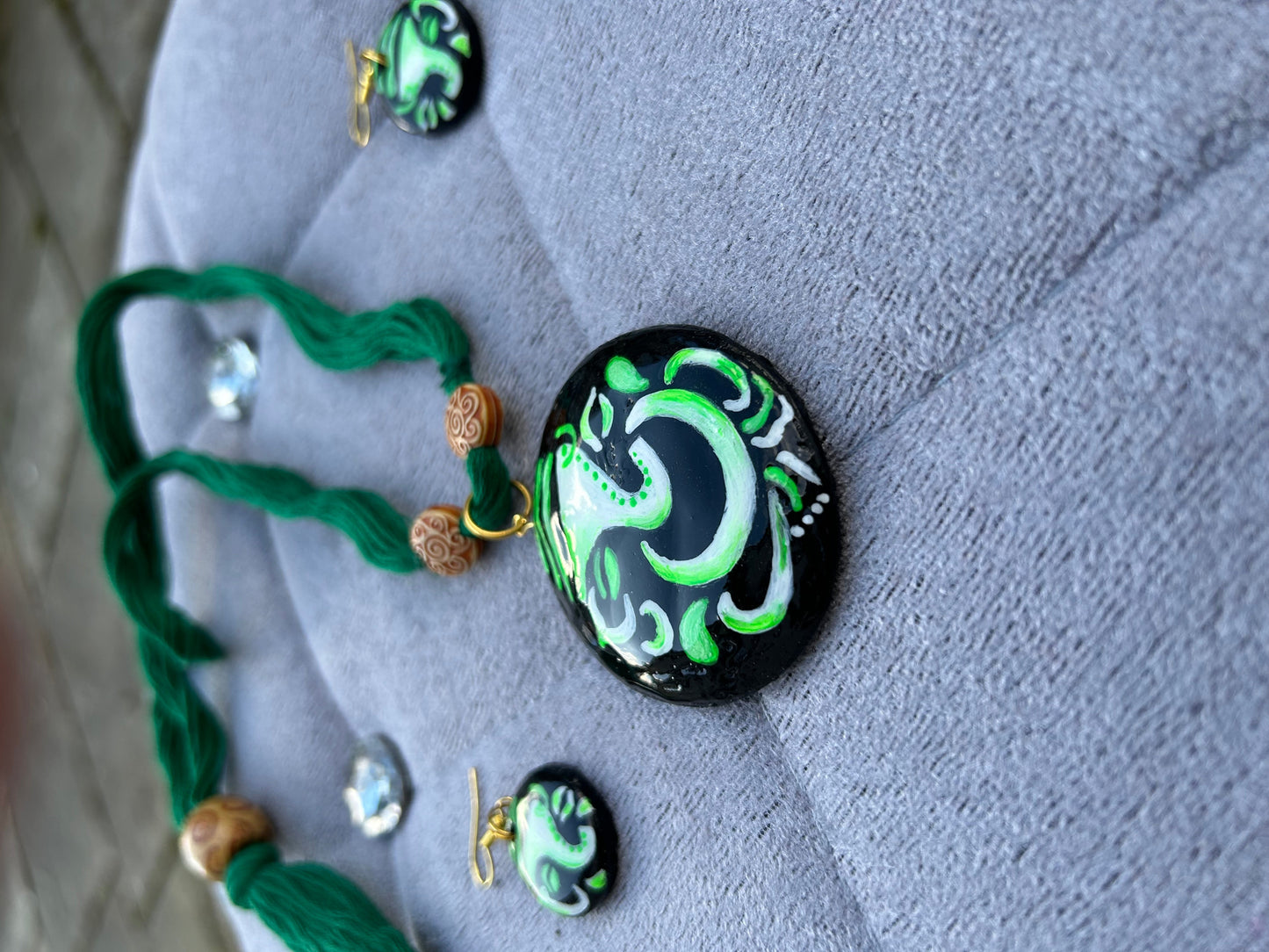Necklace with green and black pendant on a textured surface
