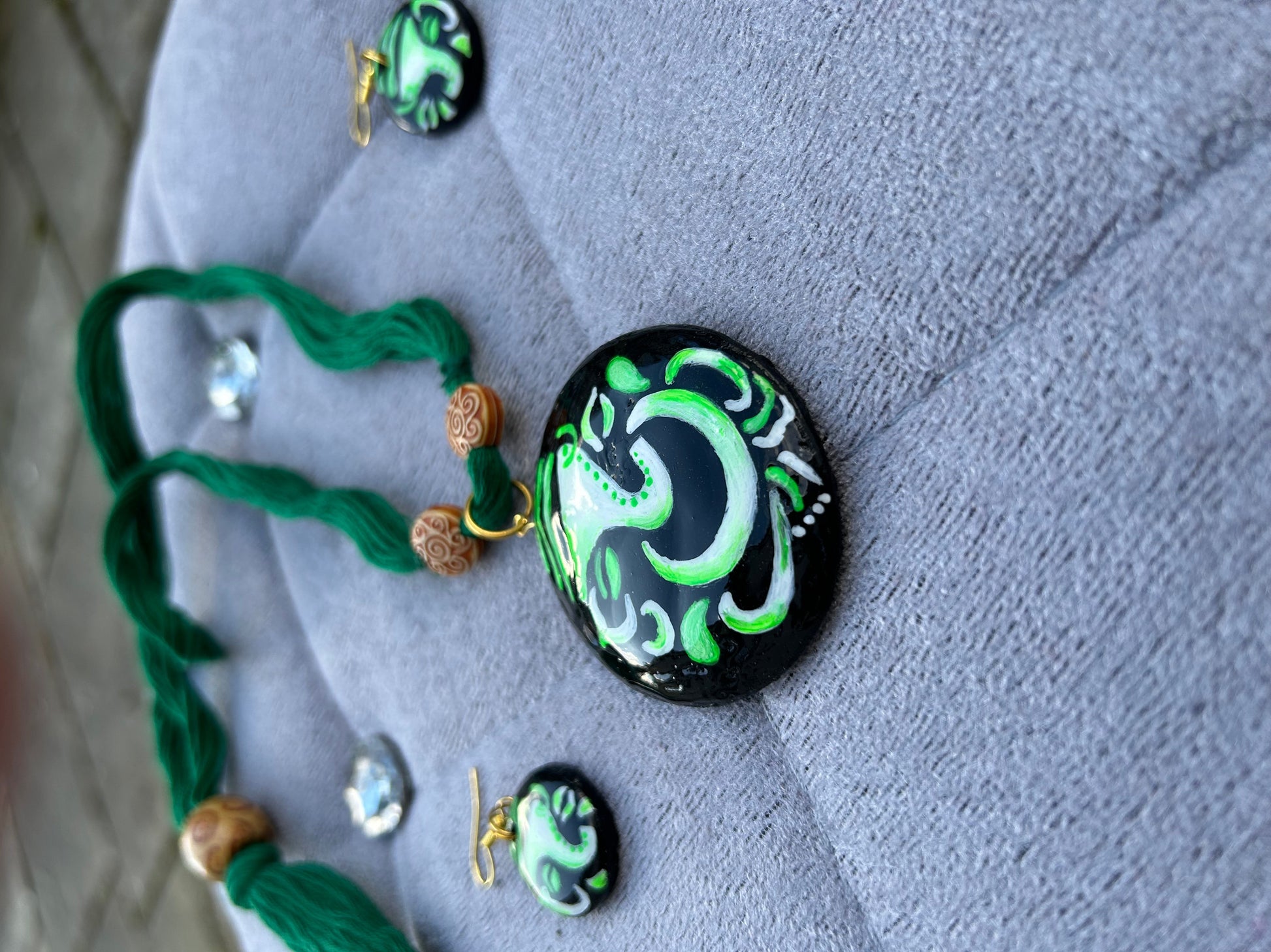 Necklace with green and black pendant on a textured surface