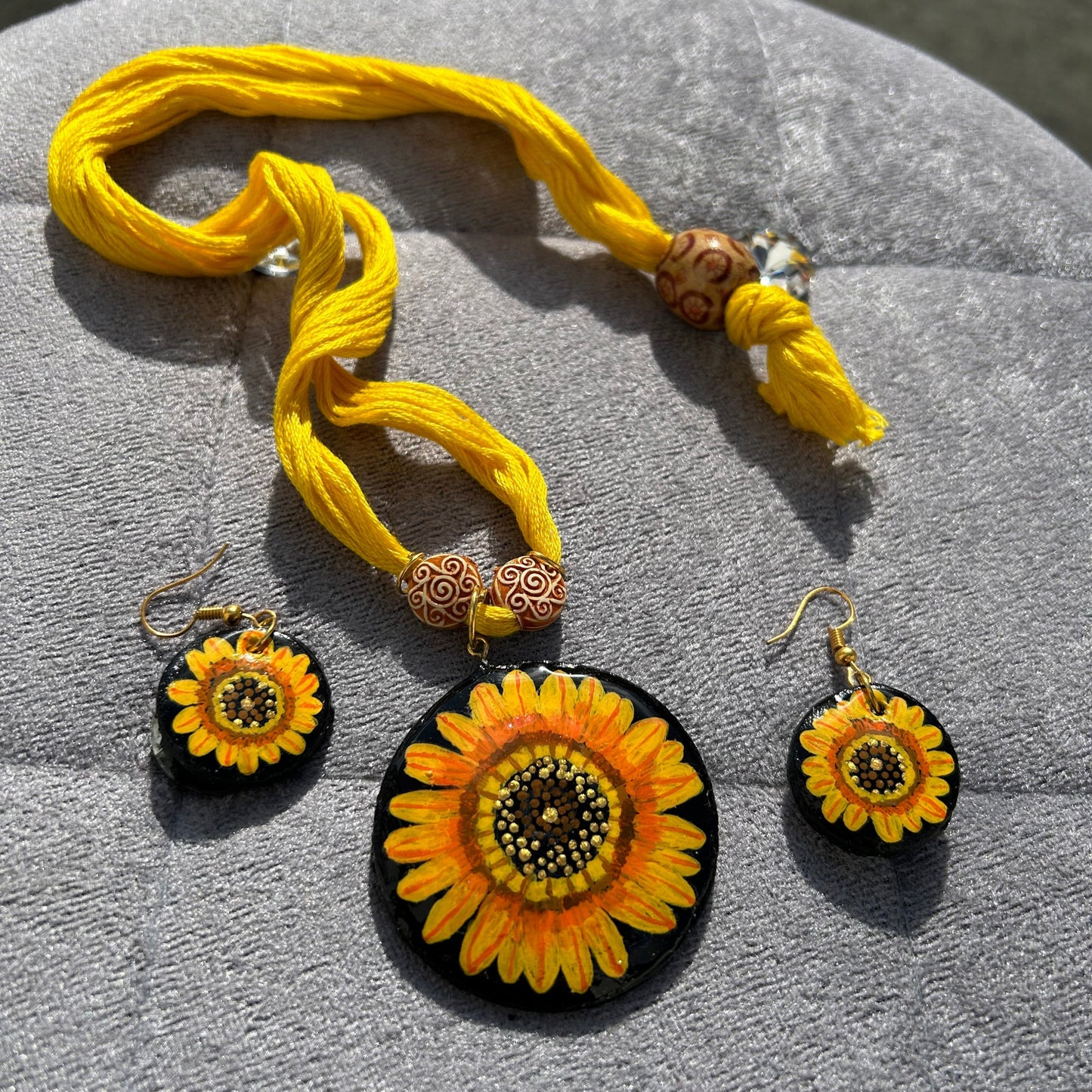 Yellow sunflower-themed jewelry set on a gray surface