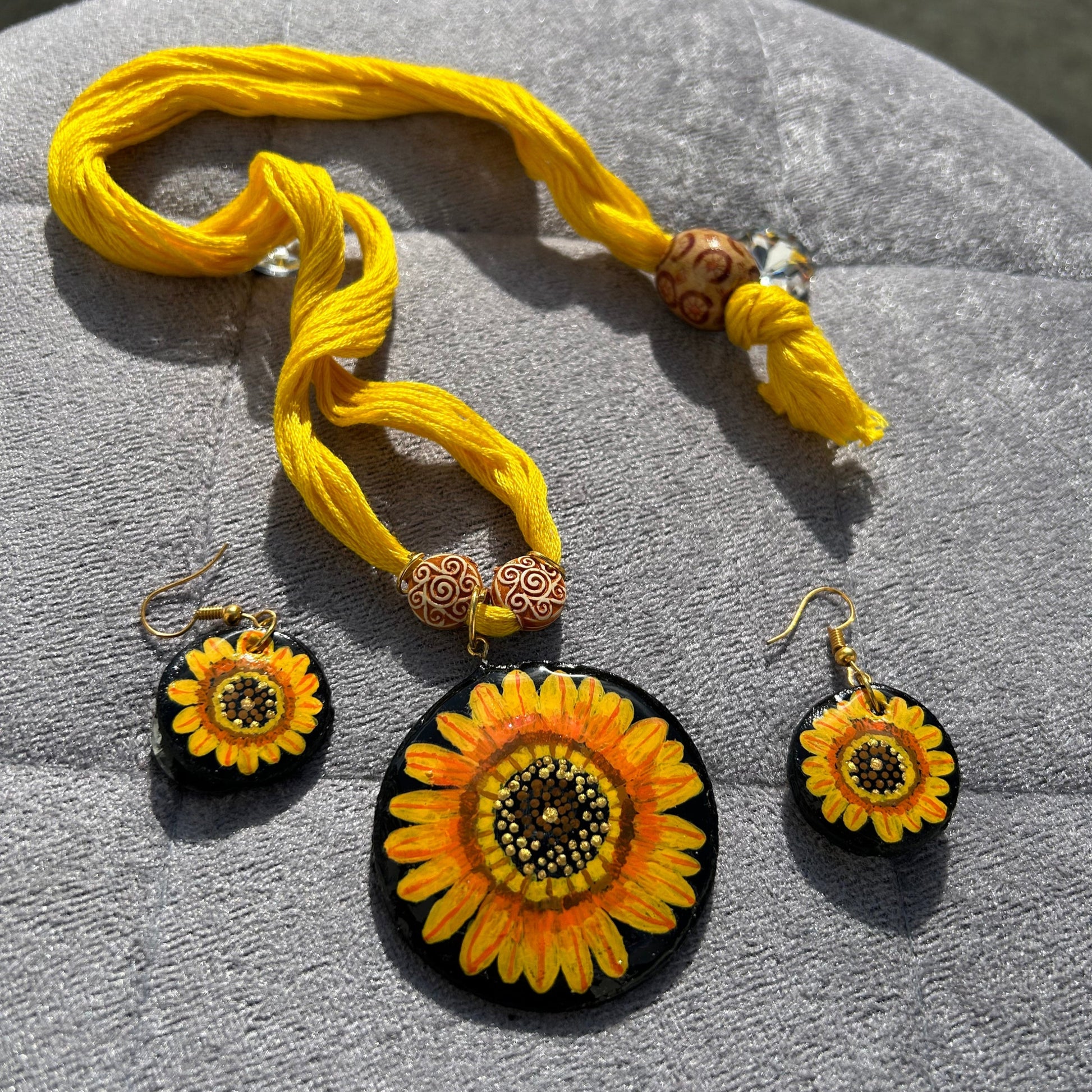 Yellow sunflower-themed jewelry set on a gray surface