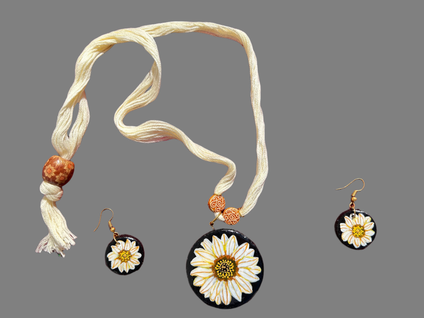 Jewelry set with necklace and earrings featuring sunflower designs on a red background