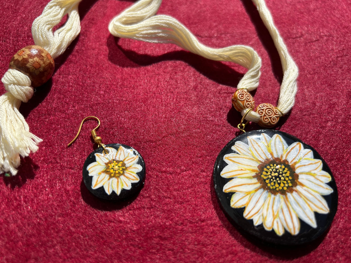 Necklace and earrings with floral designs on a red background