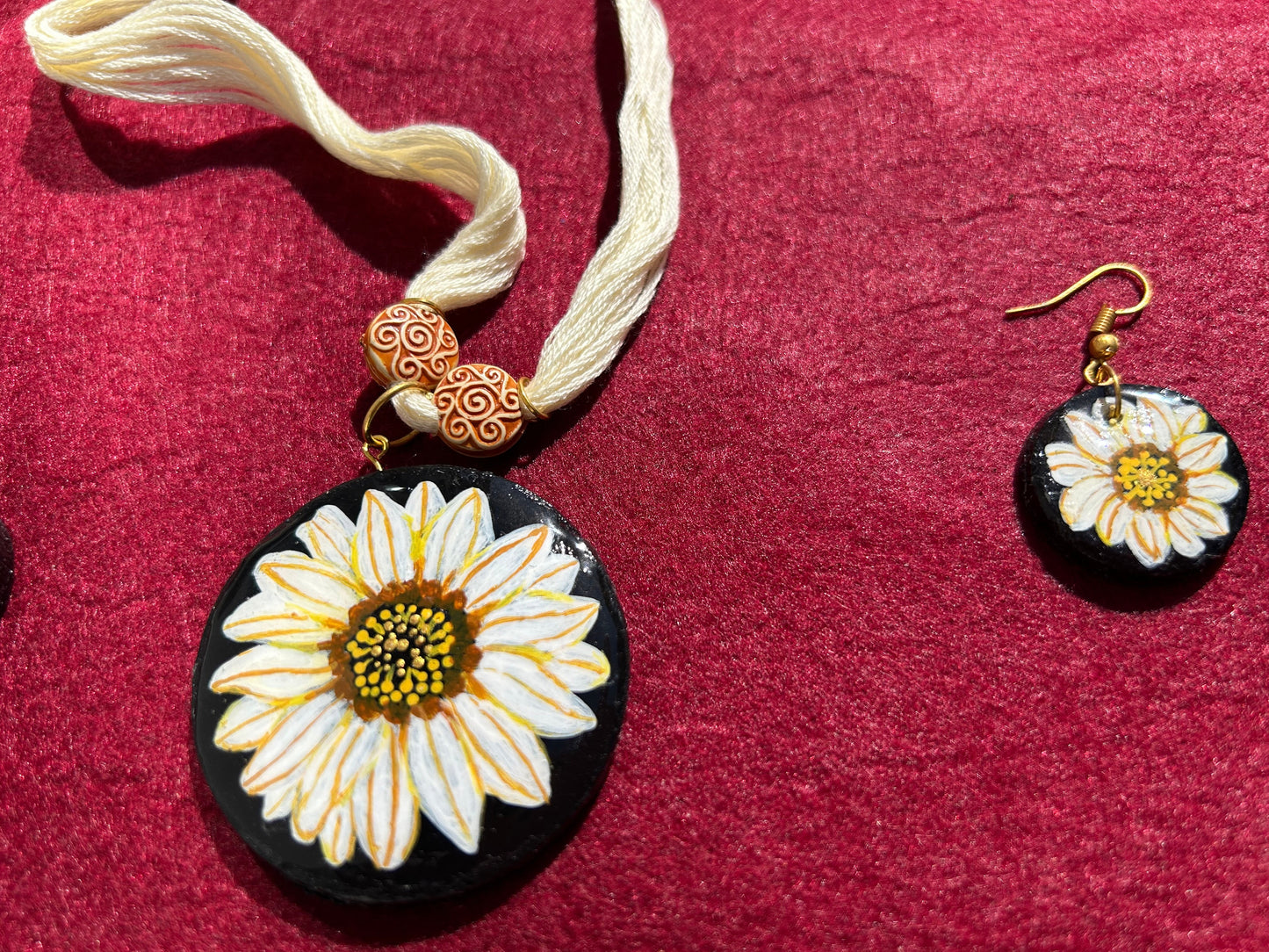 Floral pendant and earrings on a red fabric background