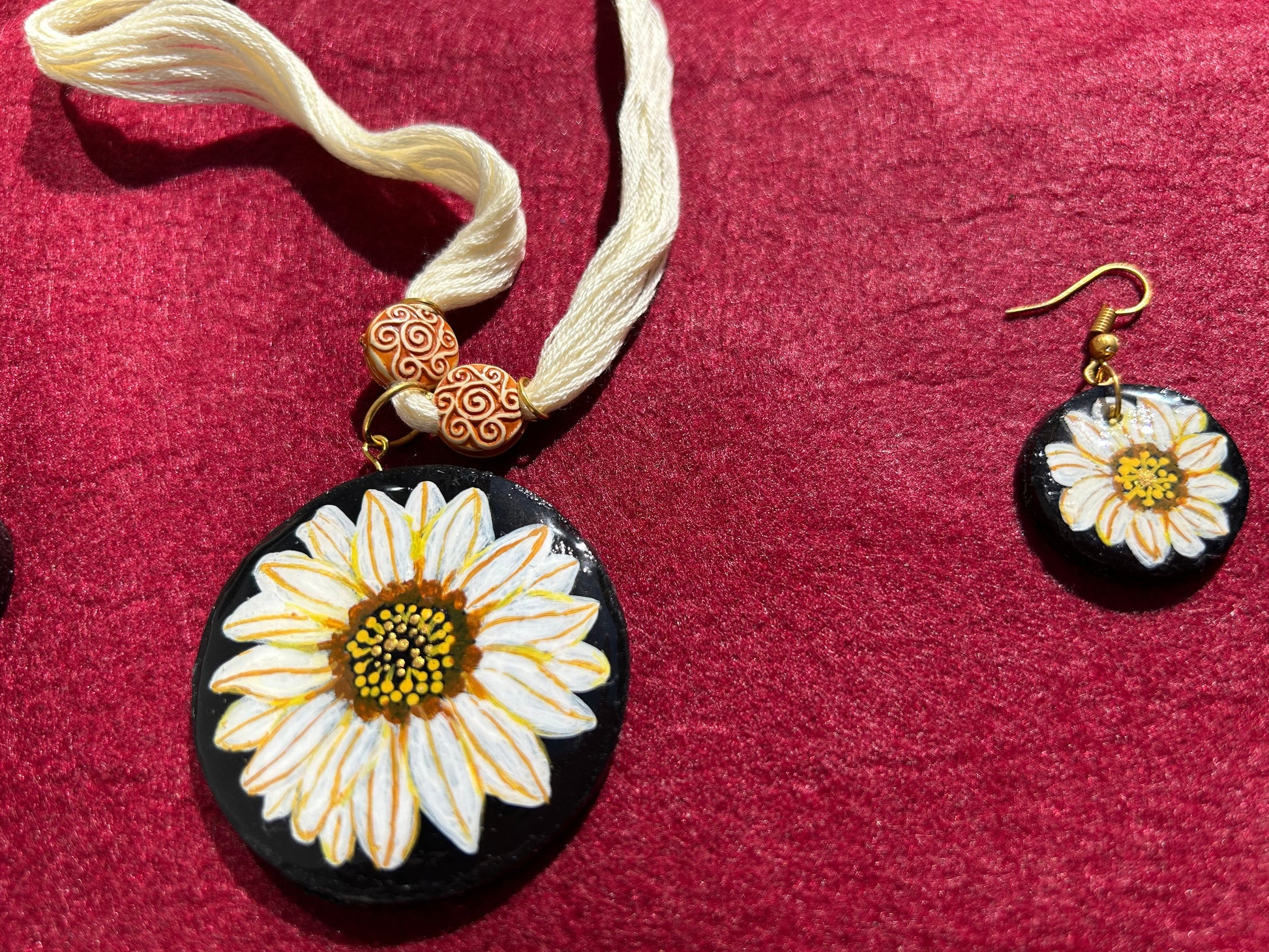 Floral pendant and earrings on a red fabric background