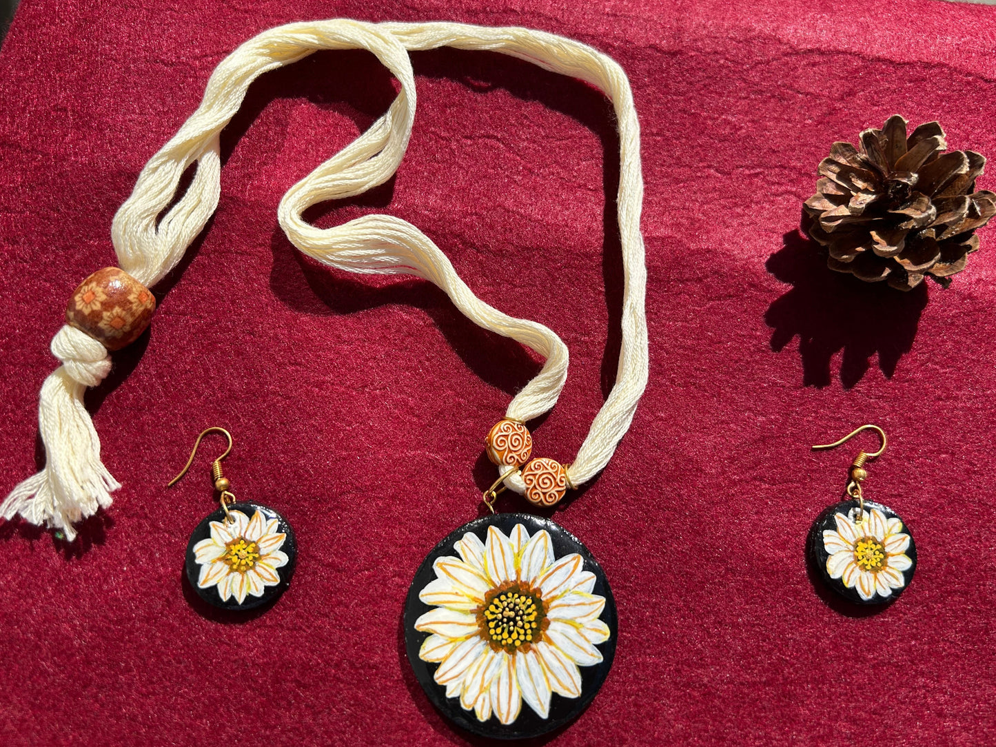 Jewelry set with sunflower-themed pendants on a red fabric background