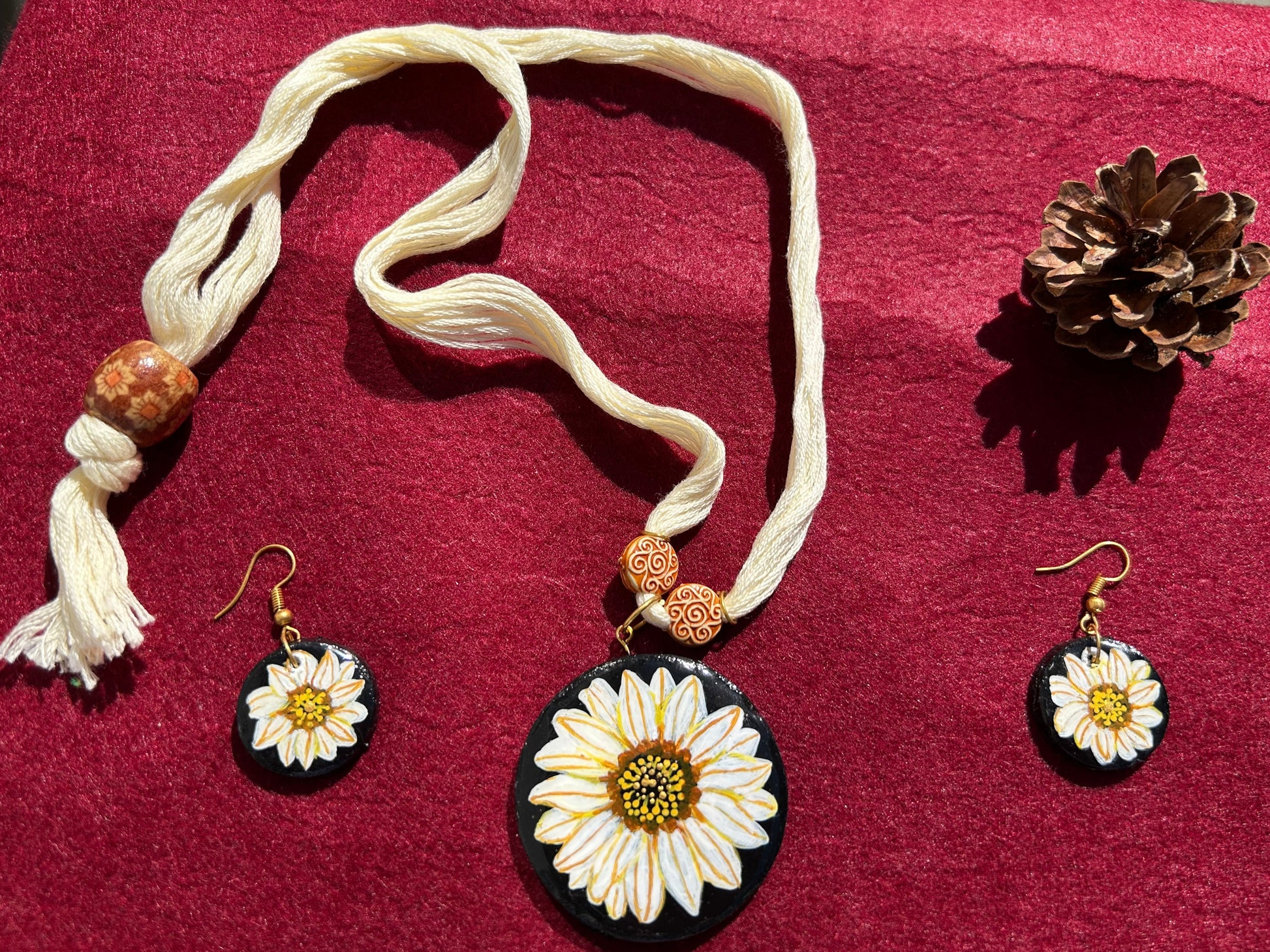 Jewelry set with sunflower-themed pendants on a red fabric background