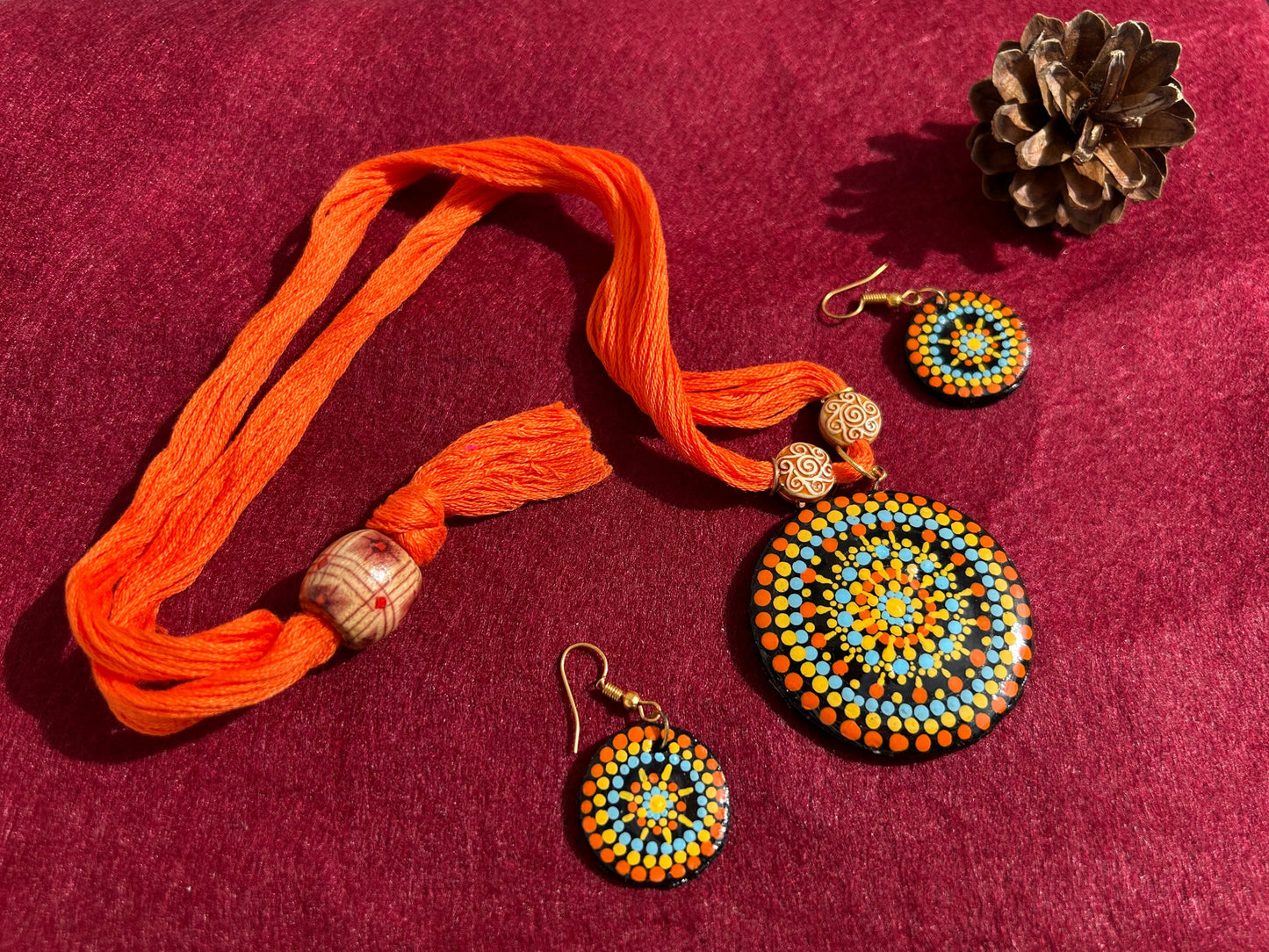 Jewelry set with orange thread bracelet and beaded earrings on a gray surface