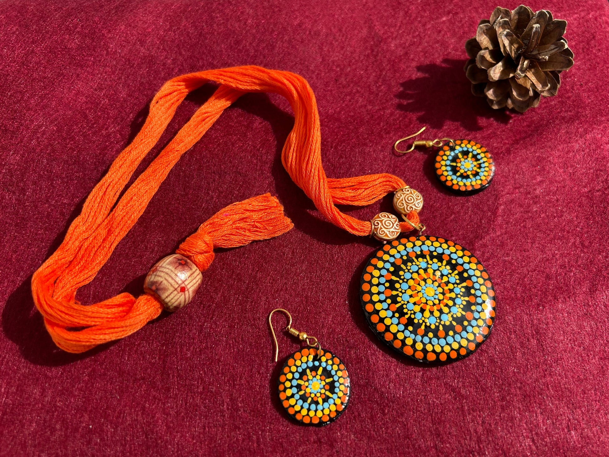 Jewelry set with orange thread bracelet and beaded earrings on a gray surface
