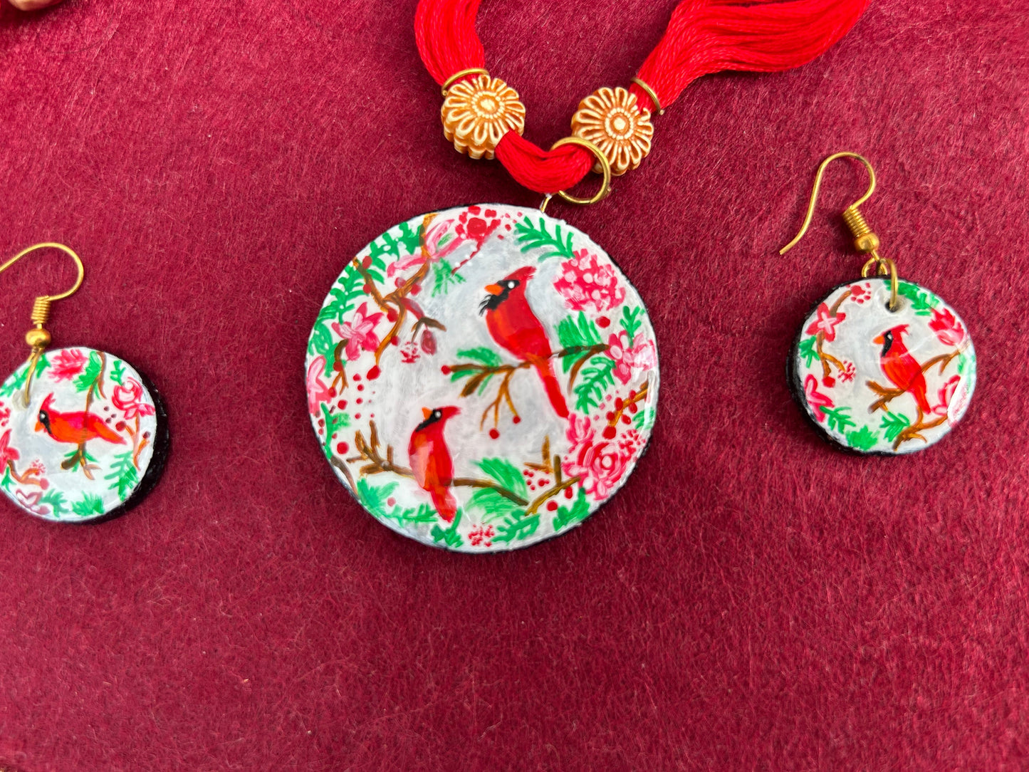 Round earrings with cardinal design on a red background