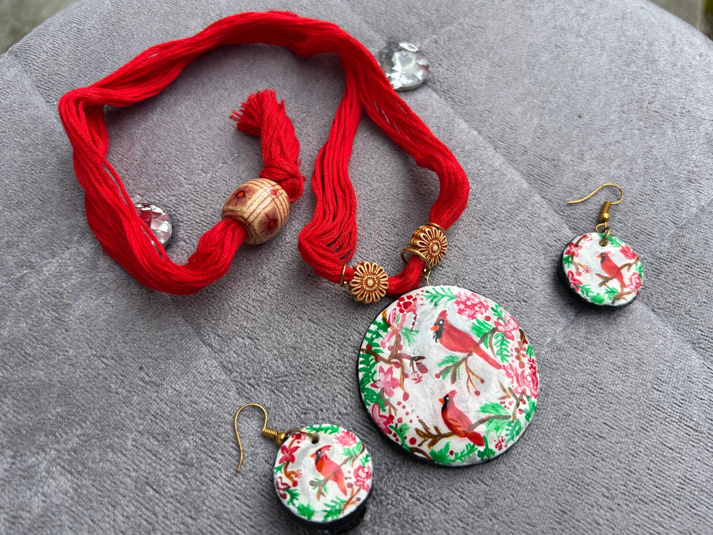 Jewelry set with red thread necklace and floral earrings on a gray surface