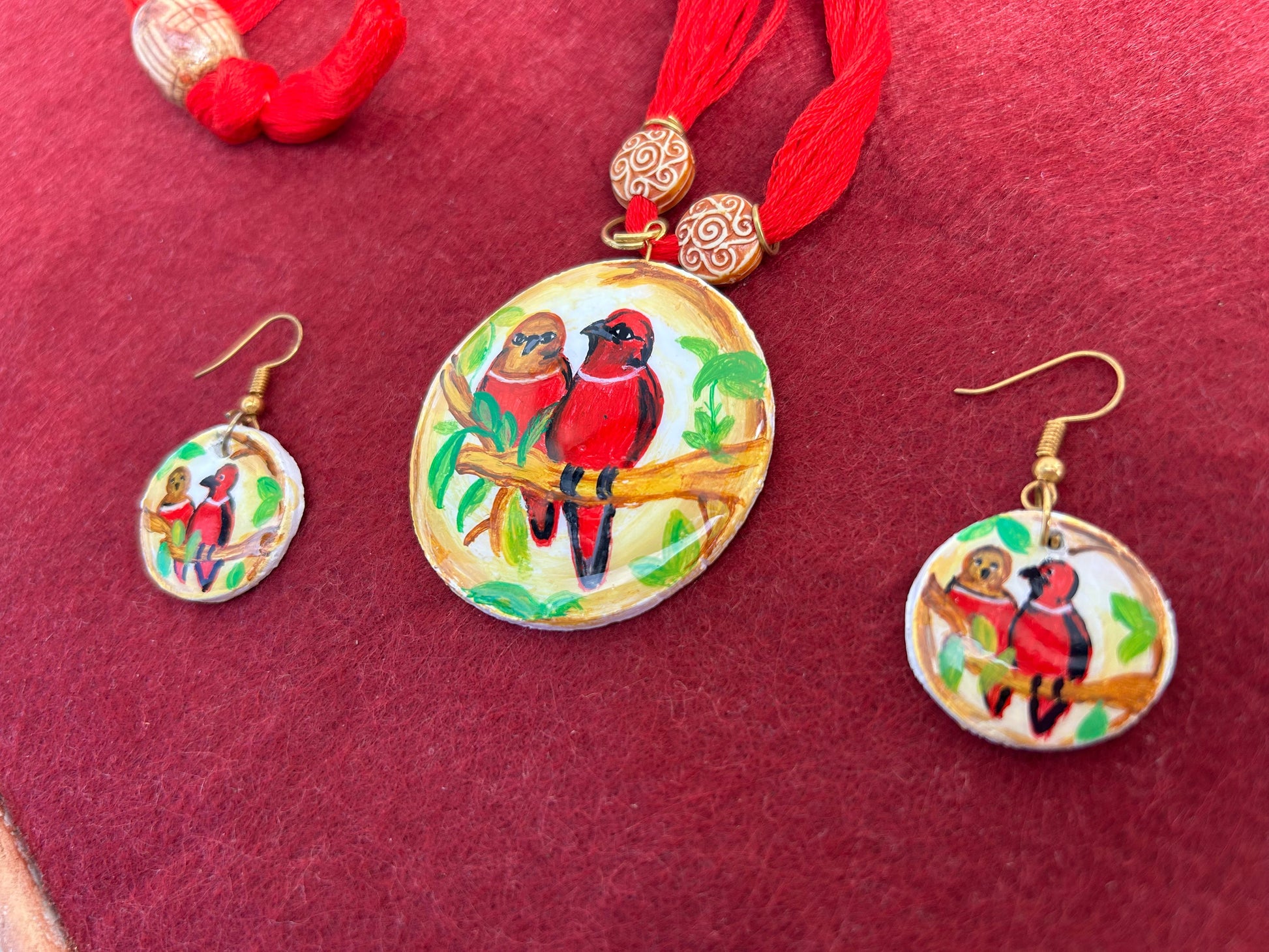 Jewelry set with circular pendant and matching earrings on a red background
