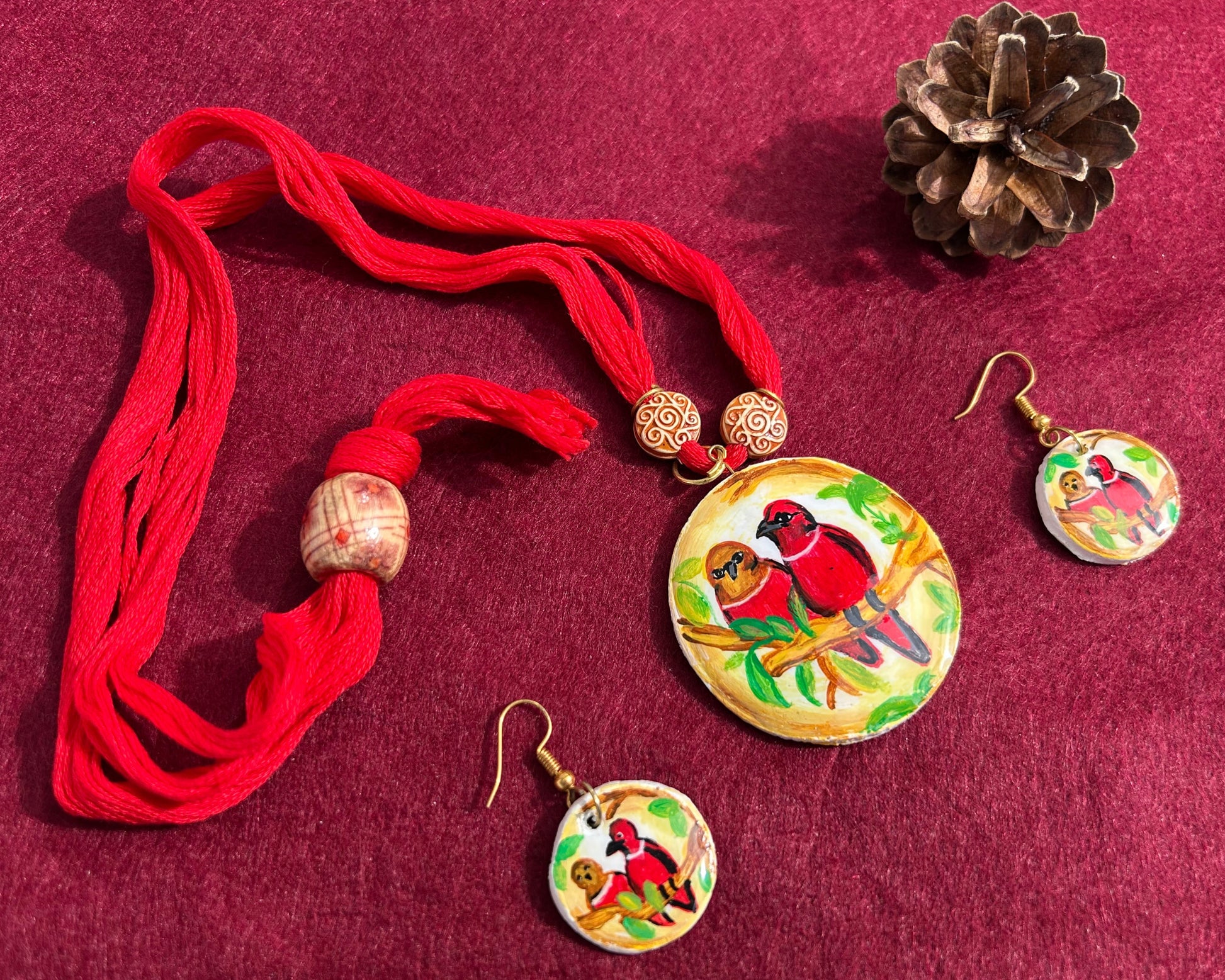 Jewelry set with red necklace and earrings on a maroon fabric background