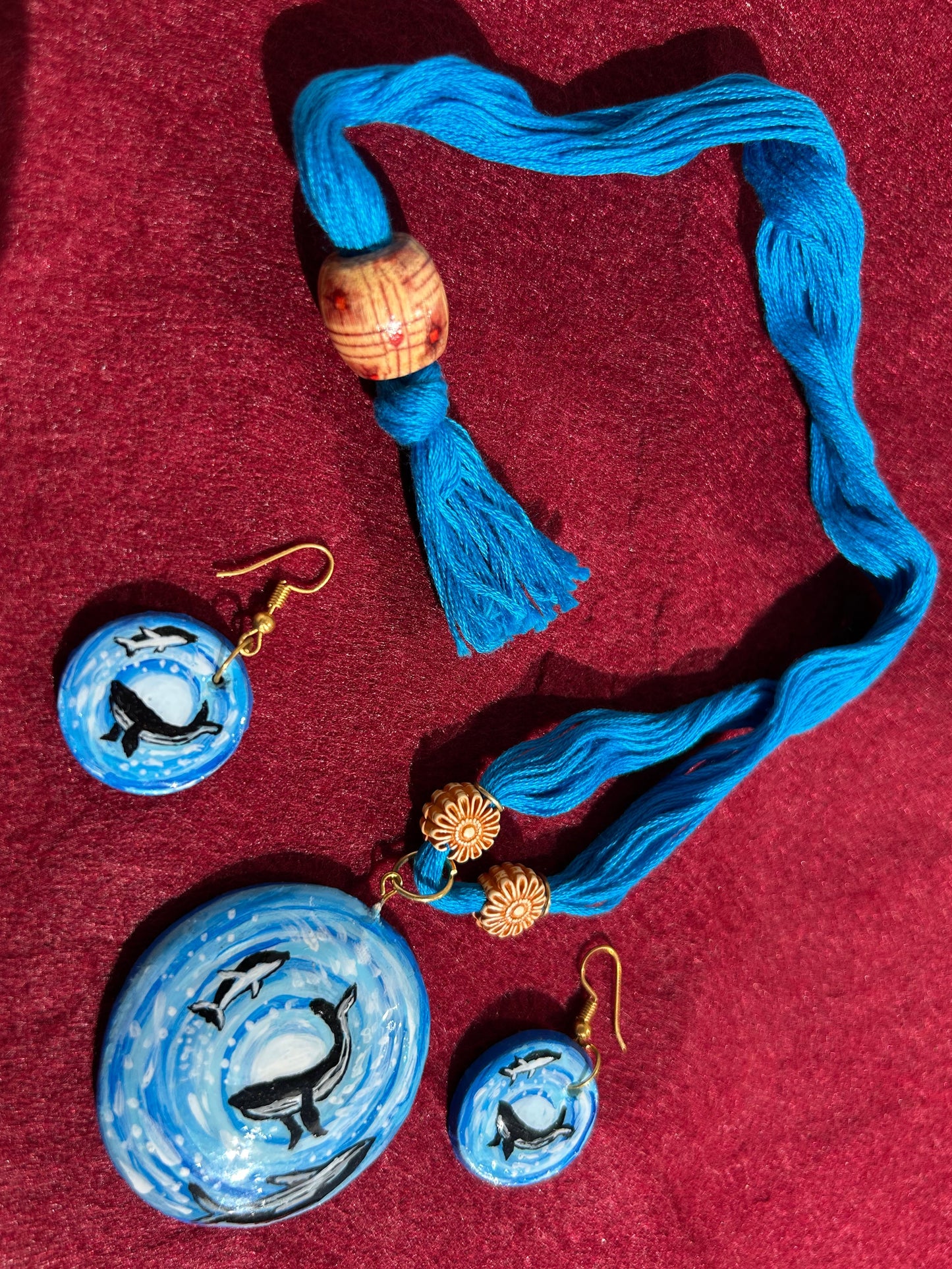Blue beaded necklace and earrings on a red fabric background