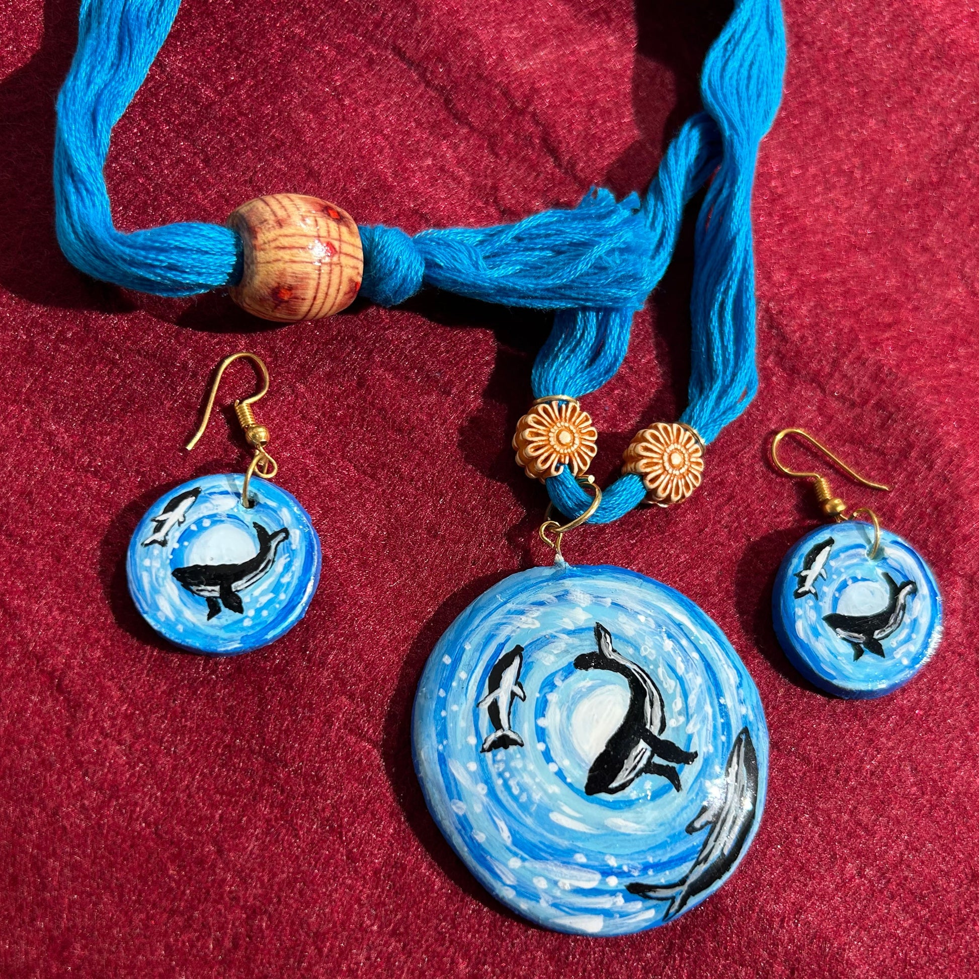 Jewelry set with blue pendant and earrings on a red fabric background