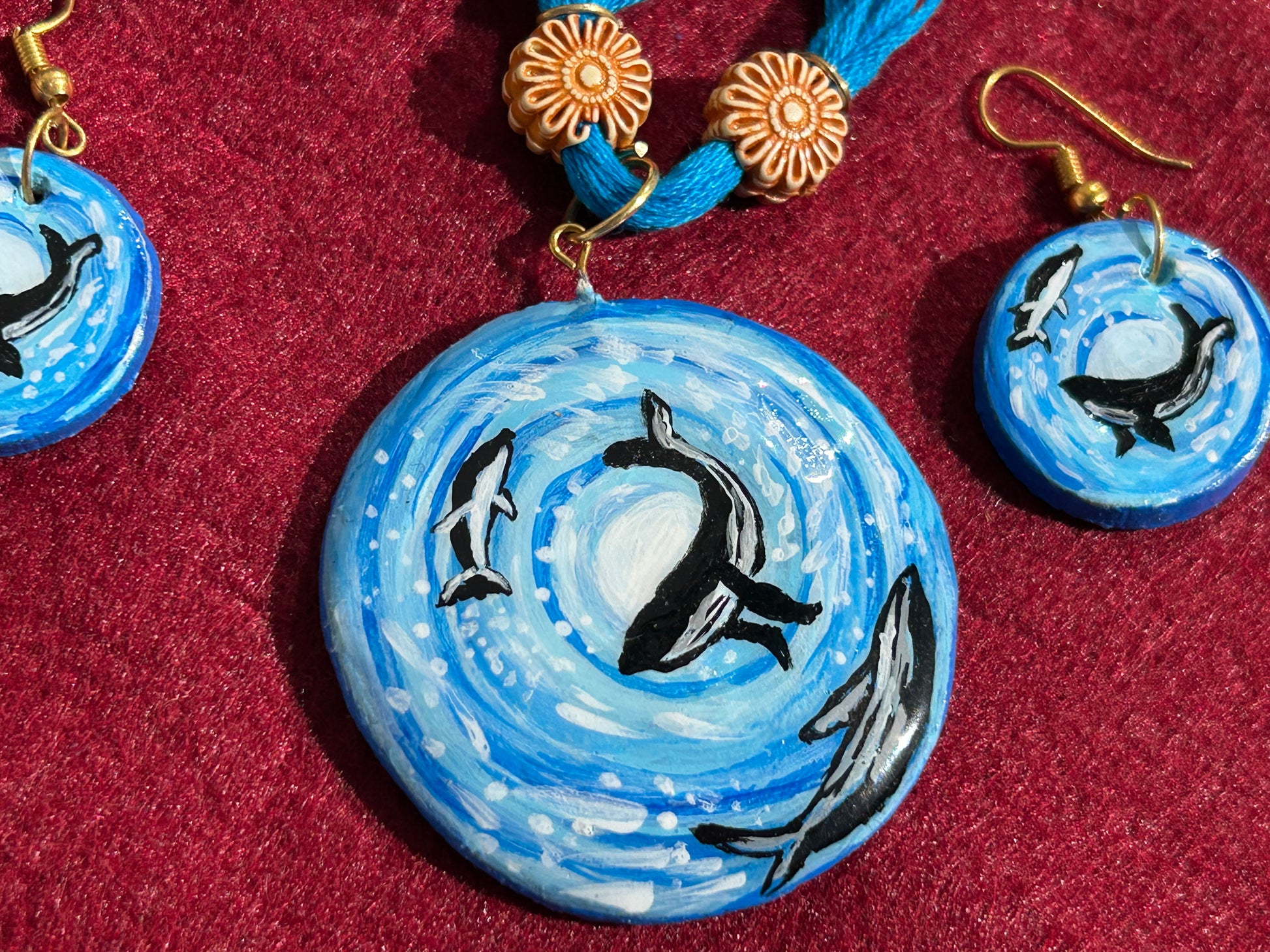 Orca whale necklace and earrings set on a red background