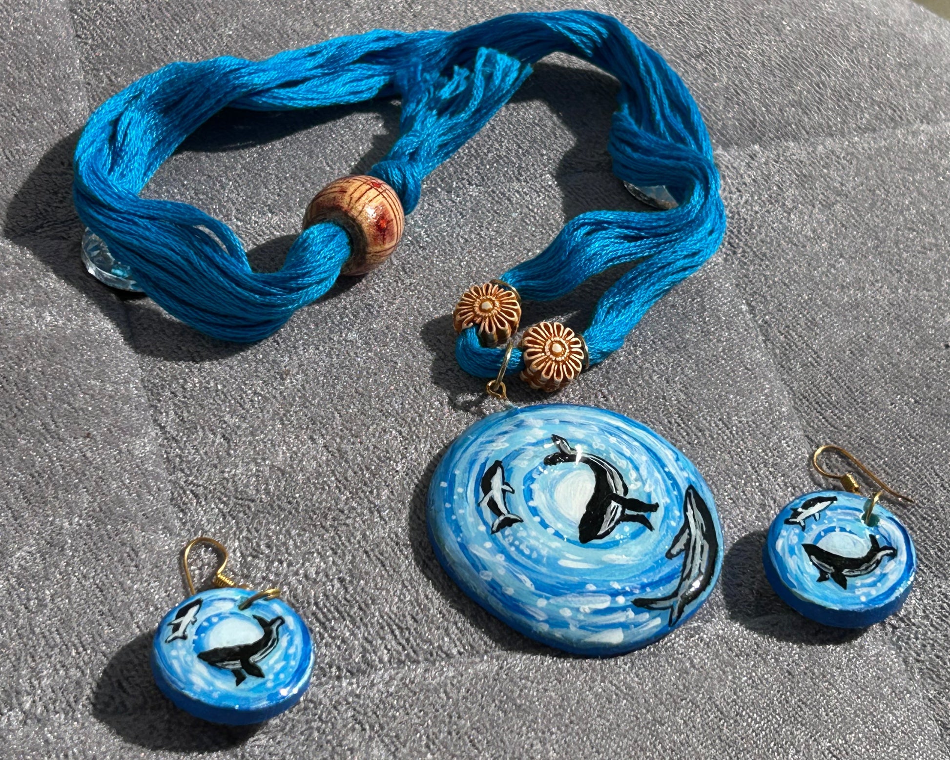 Blue jewelry set with penguin charms on a stone surface