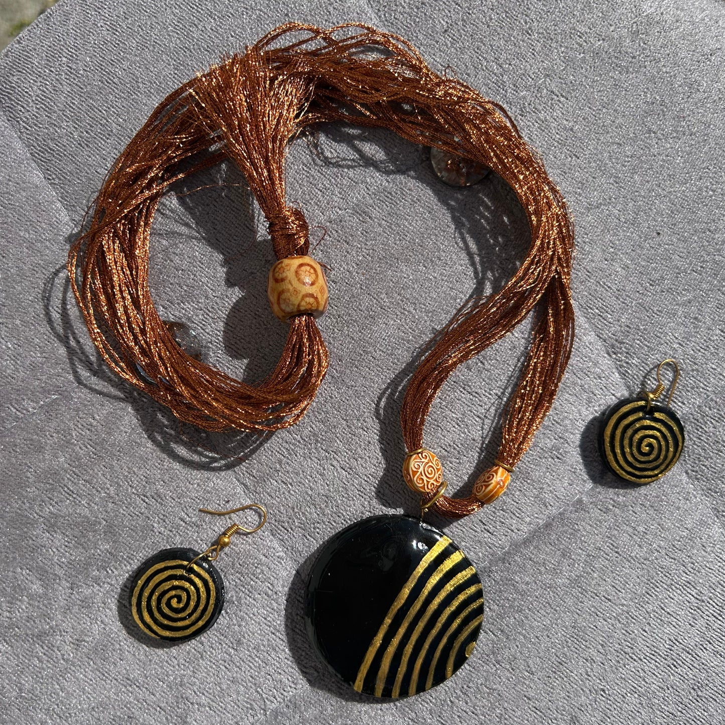 Jewelry set with a necklace and earrings featuring spiral designs on a textured surface.