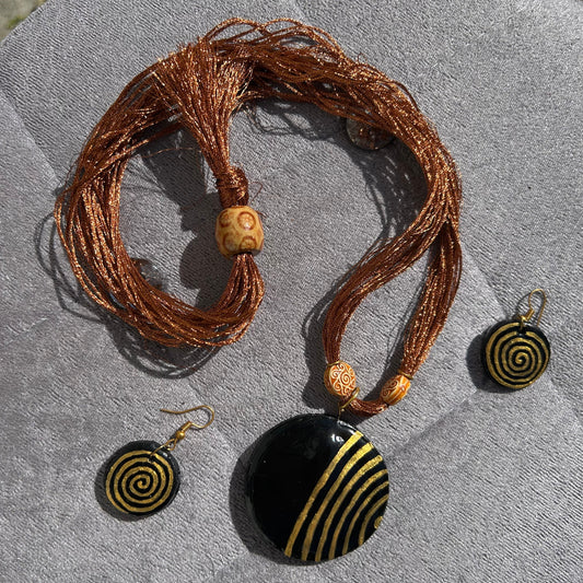 Jewelry set with a necklace and earrings featuring spiral designs on a textured surface.
