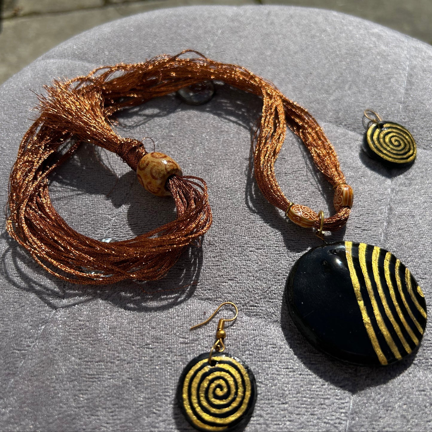 Jewelry set with a bracelet and two spiral-patterned earrings on a gray surface.