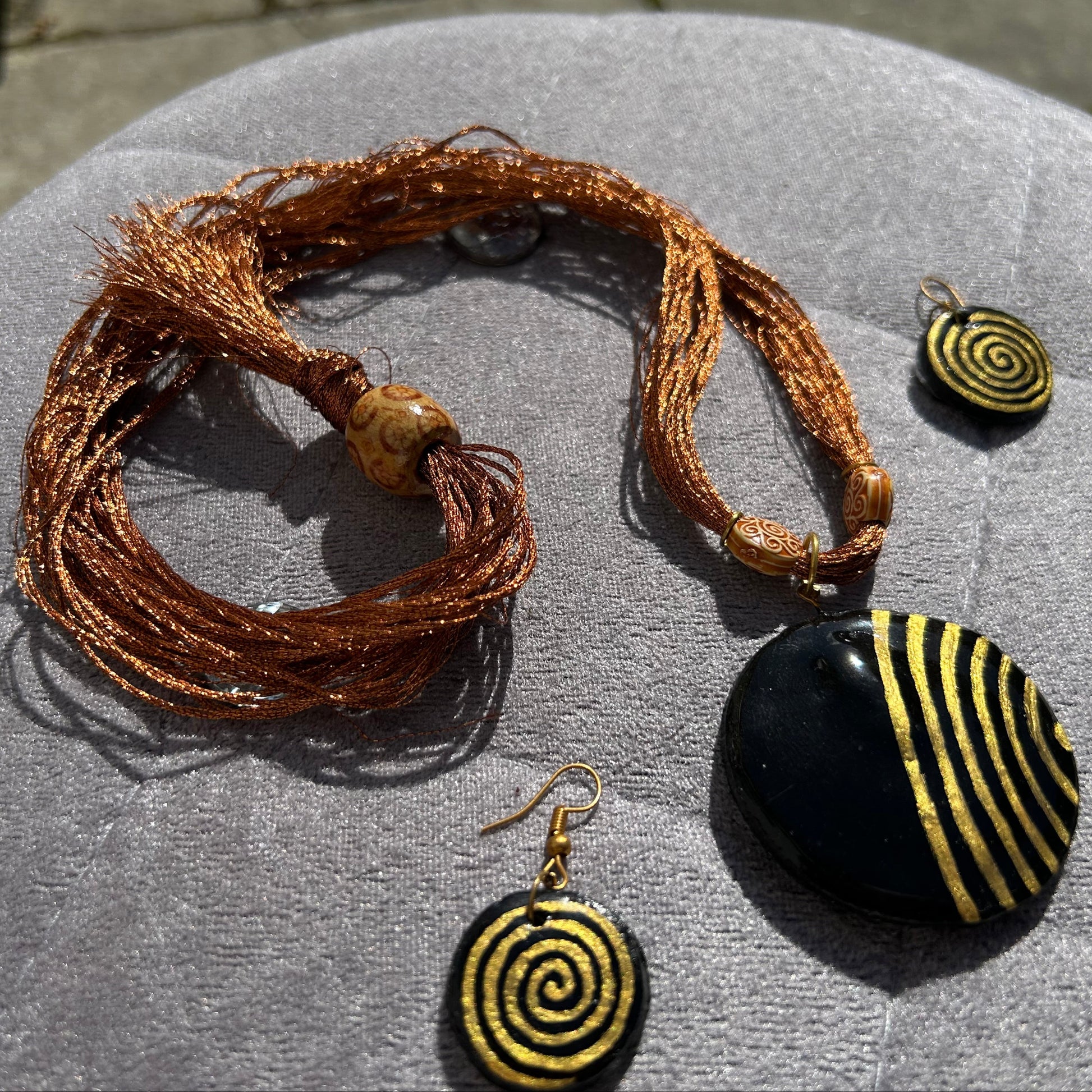 Jewelry set with a bracelet and two spiral-patterned earrings on a gray surface.