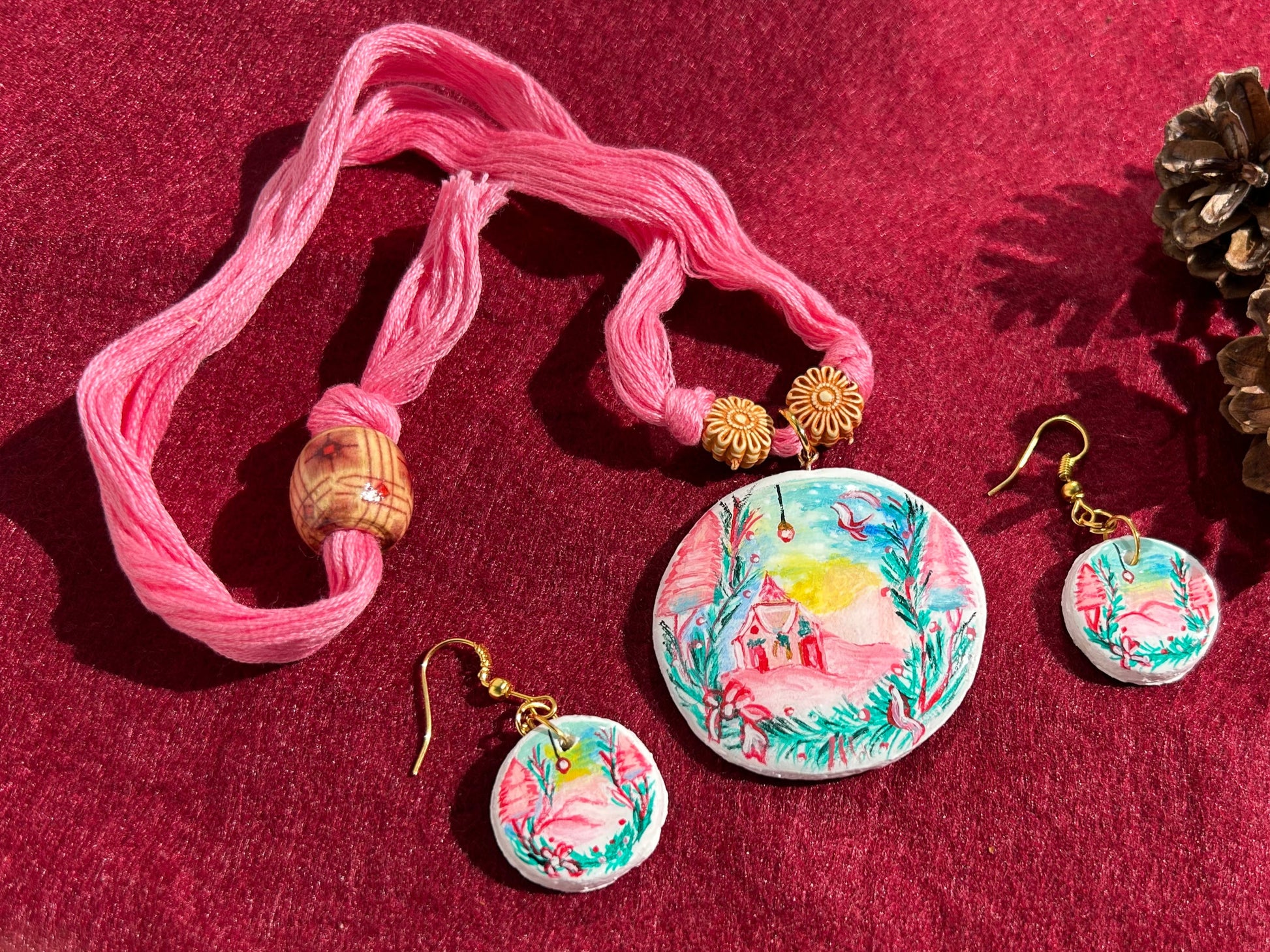 Jewelry set with pink hair tie, floral earrings, and pendants on a red background