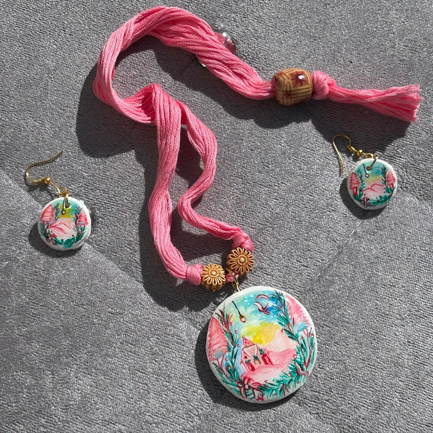 Jewelry set with floral earrings and a pink ribbon on a gray surface