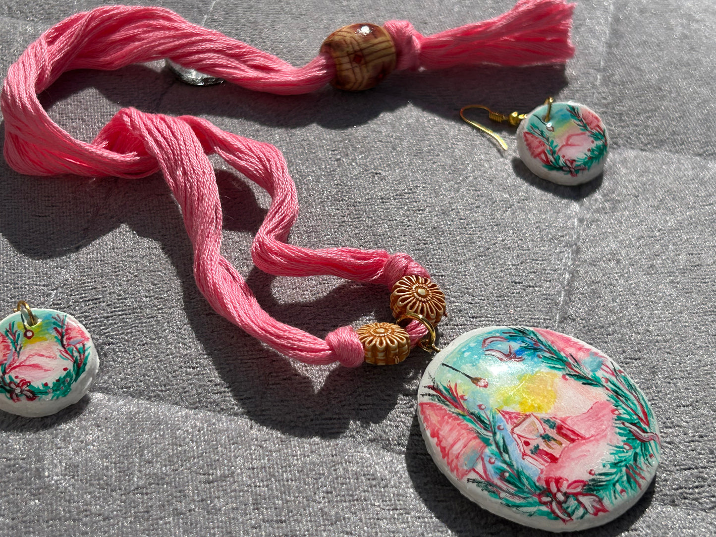 Set of floral earrings with pink thread on a gray surface