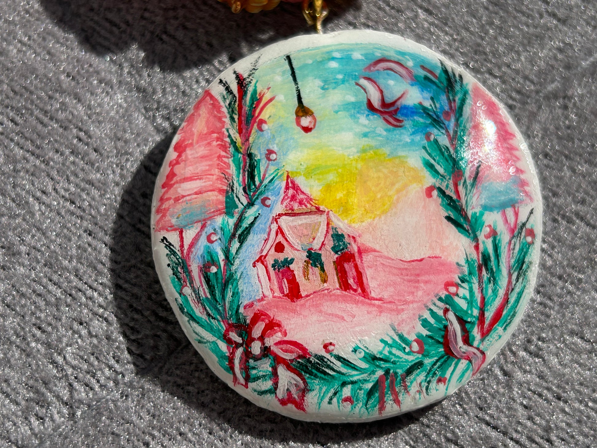 Decorative button with a hand-painted design of a house and trees on a textured surface