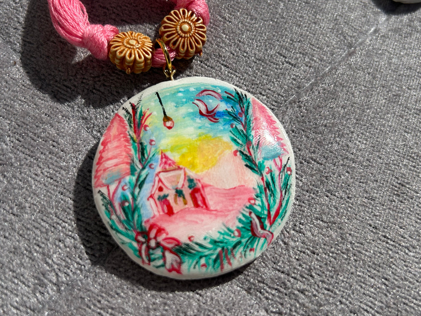 Decorative button with a pink house design on a textured surface