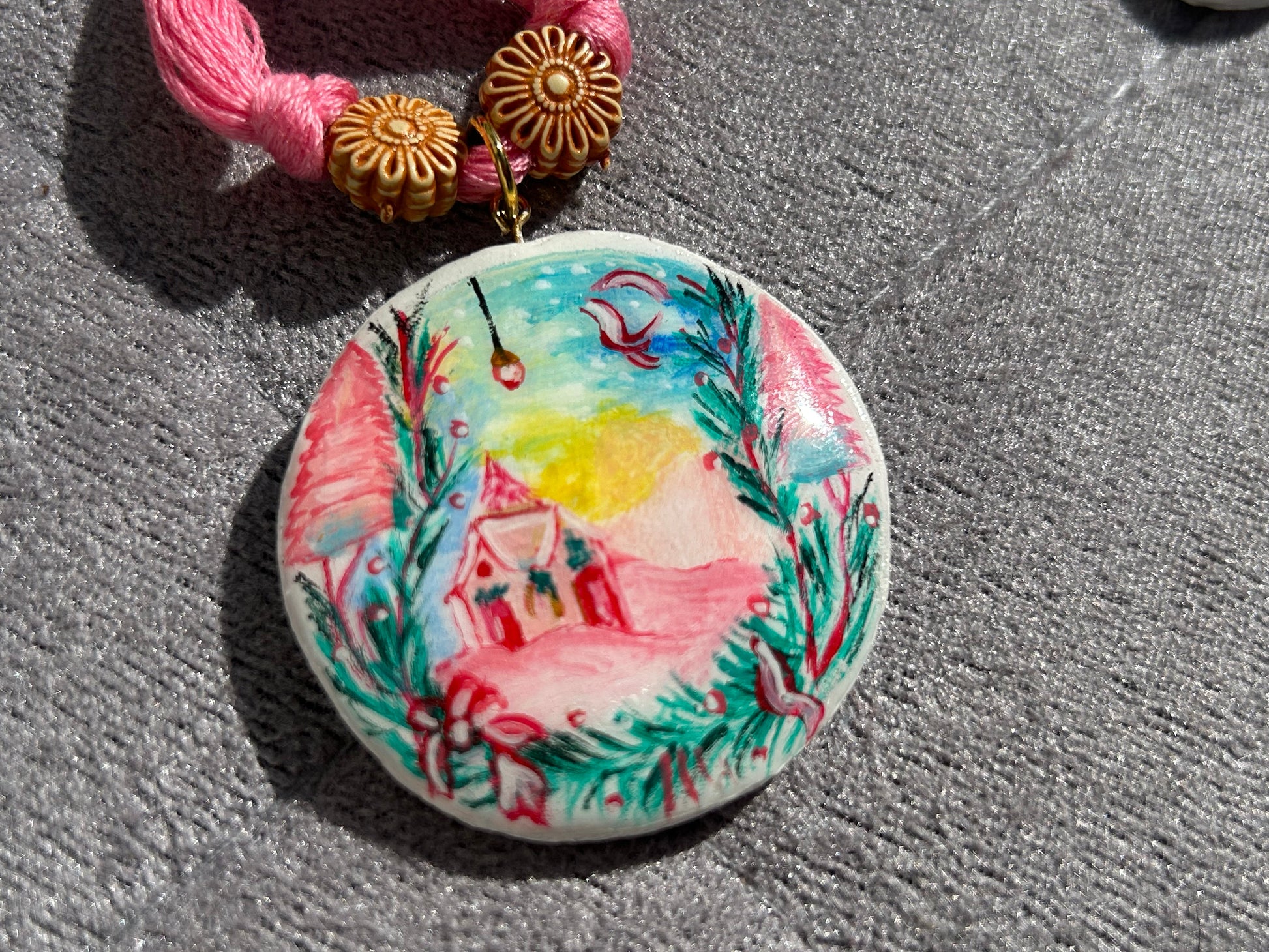 Decorative button with a pink house design on a textured surface