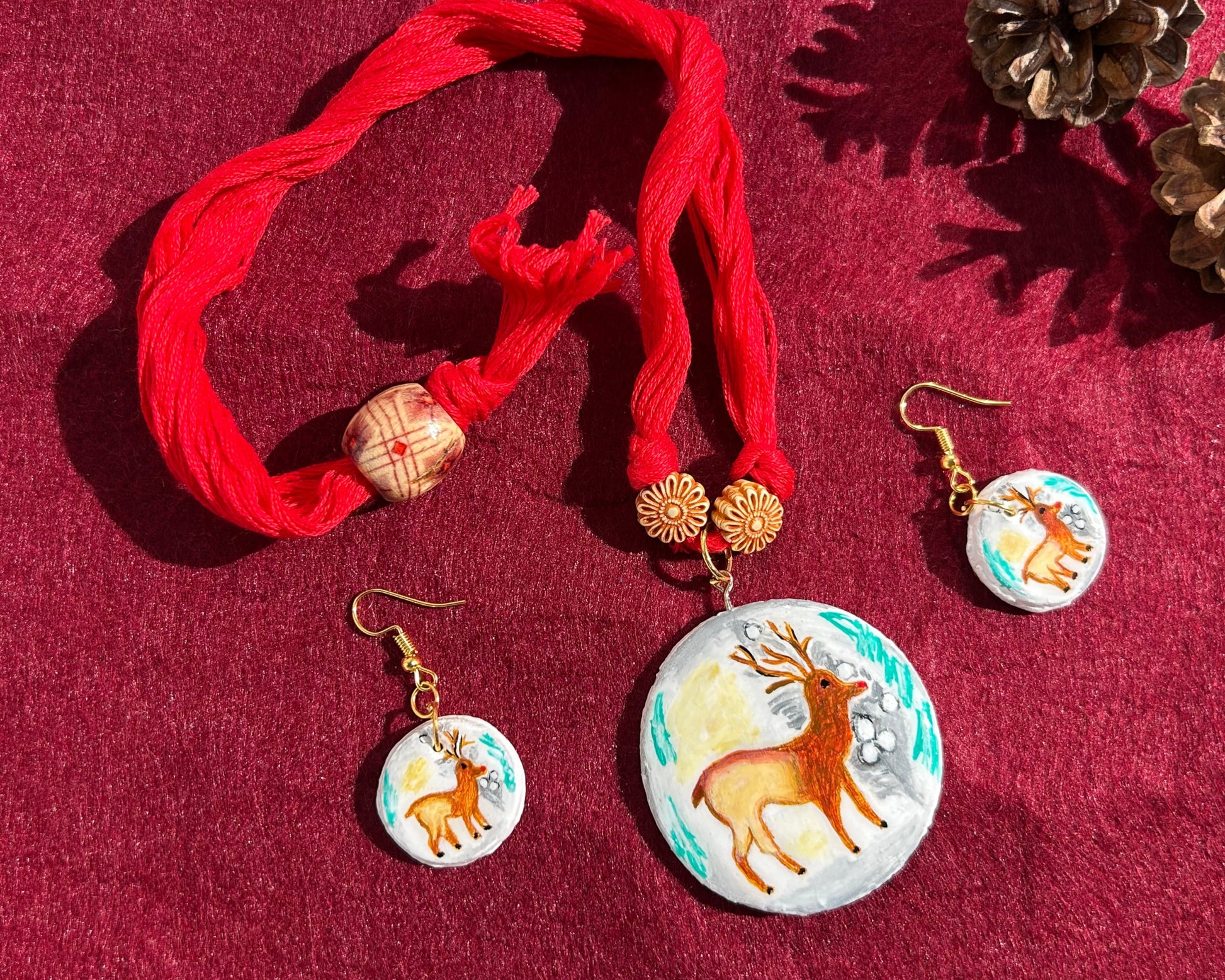 Jewelry set with red fabric, earrings, and a necklace on a red background