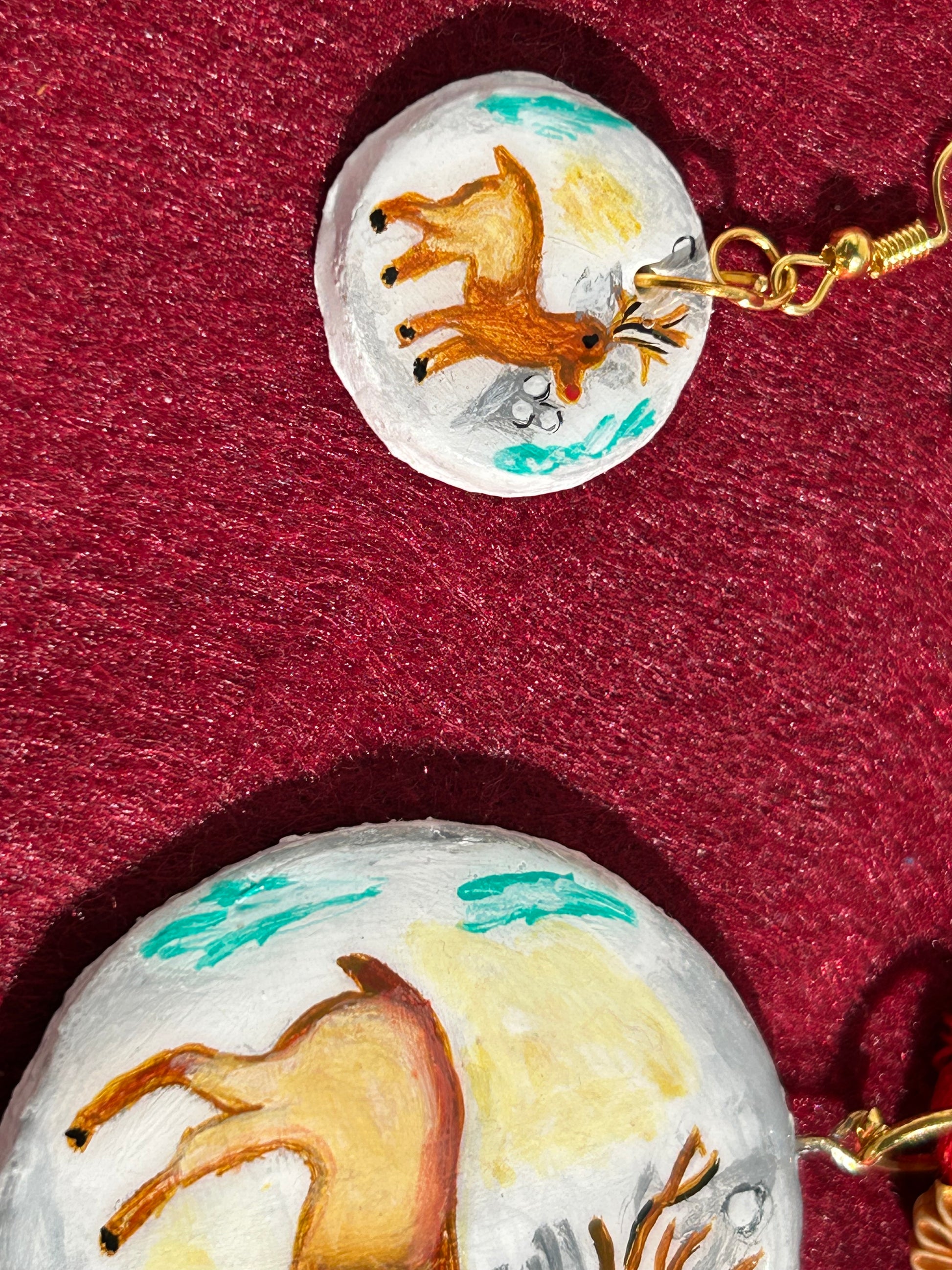 Deer-themed earrings on a red background