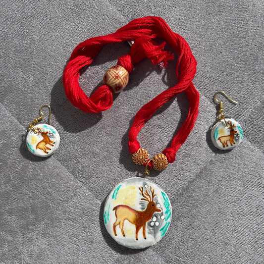 Bracelet with red fabric and deer-themed charms on a gray surface