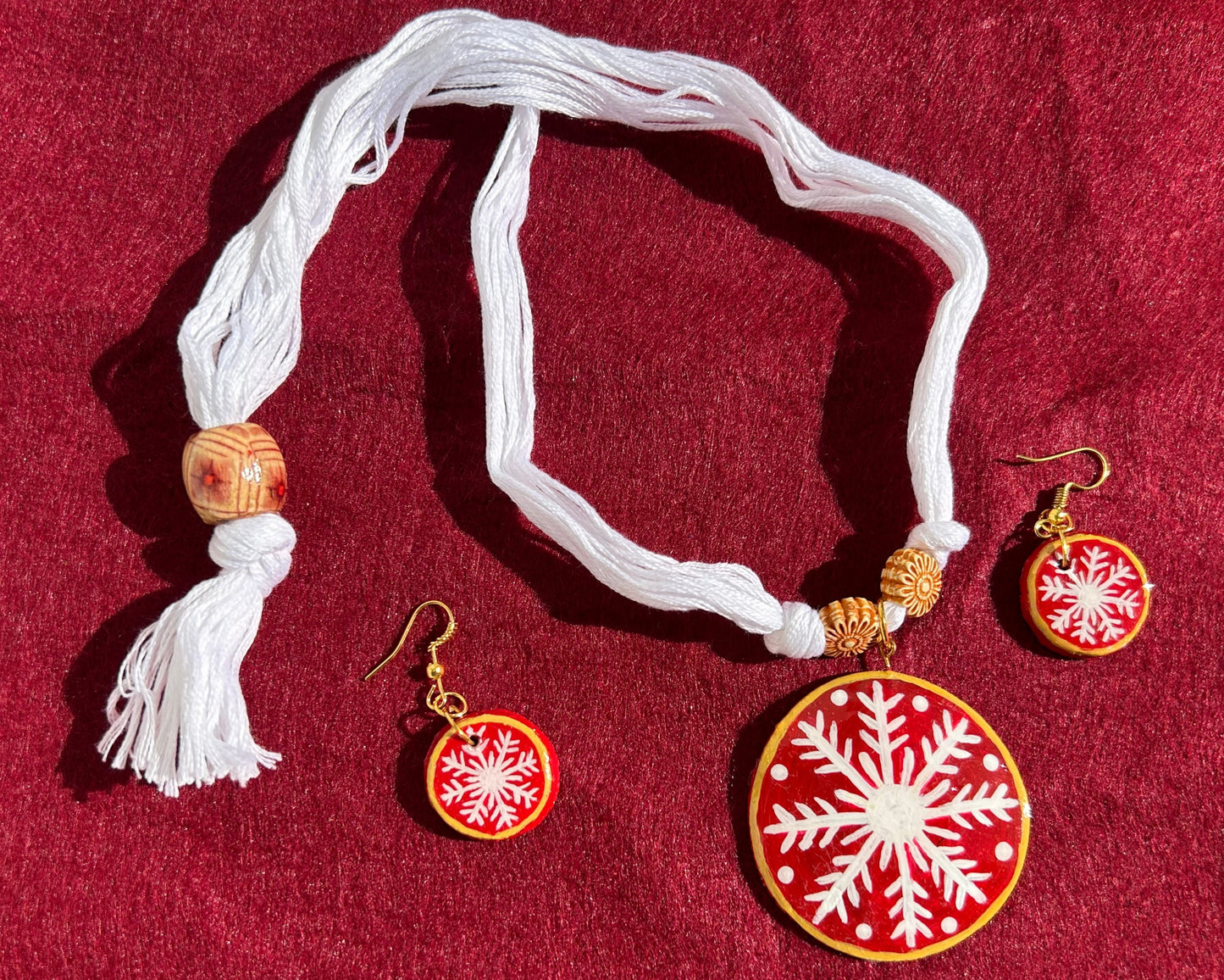 Necklace with snowflake pendant and matching earrings on a red background