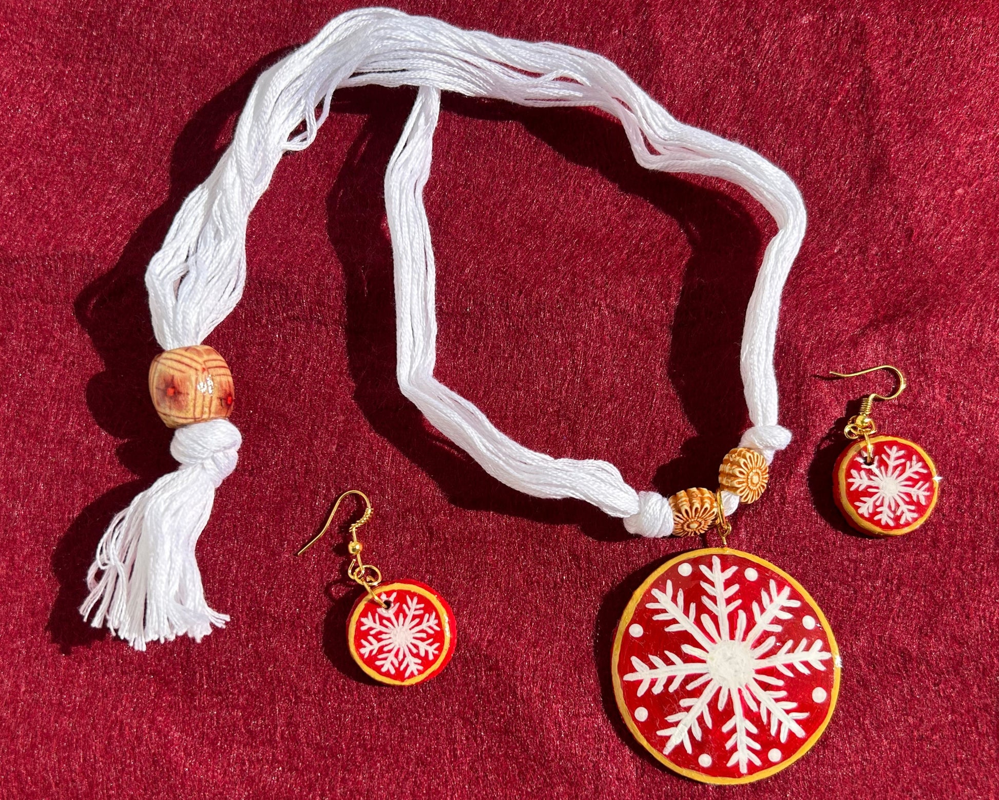 Necklace with snowflake pendant and matching earrings on a red background