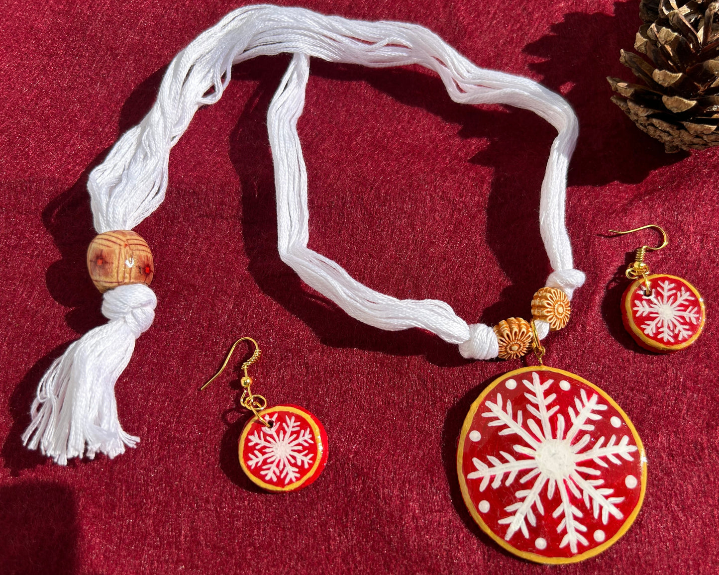 Jewelry set with necklace and earrings featuring snowflake designs on a red background