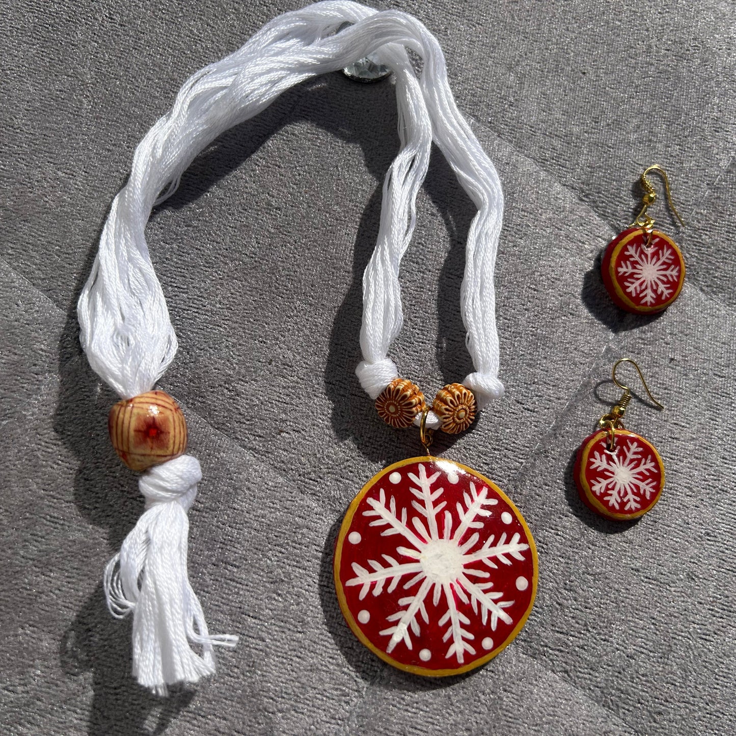 Necklace and earrings with snowflake designs on a textured surface